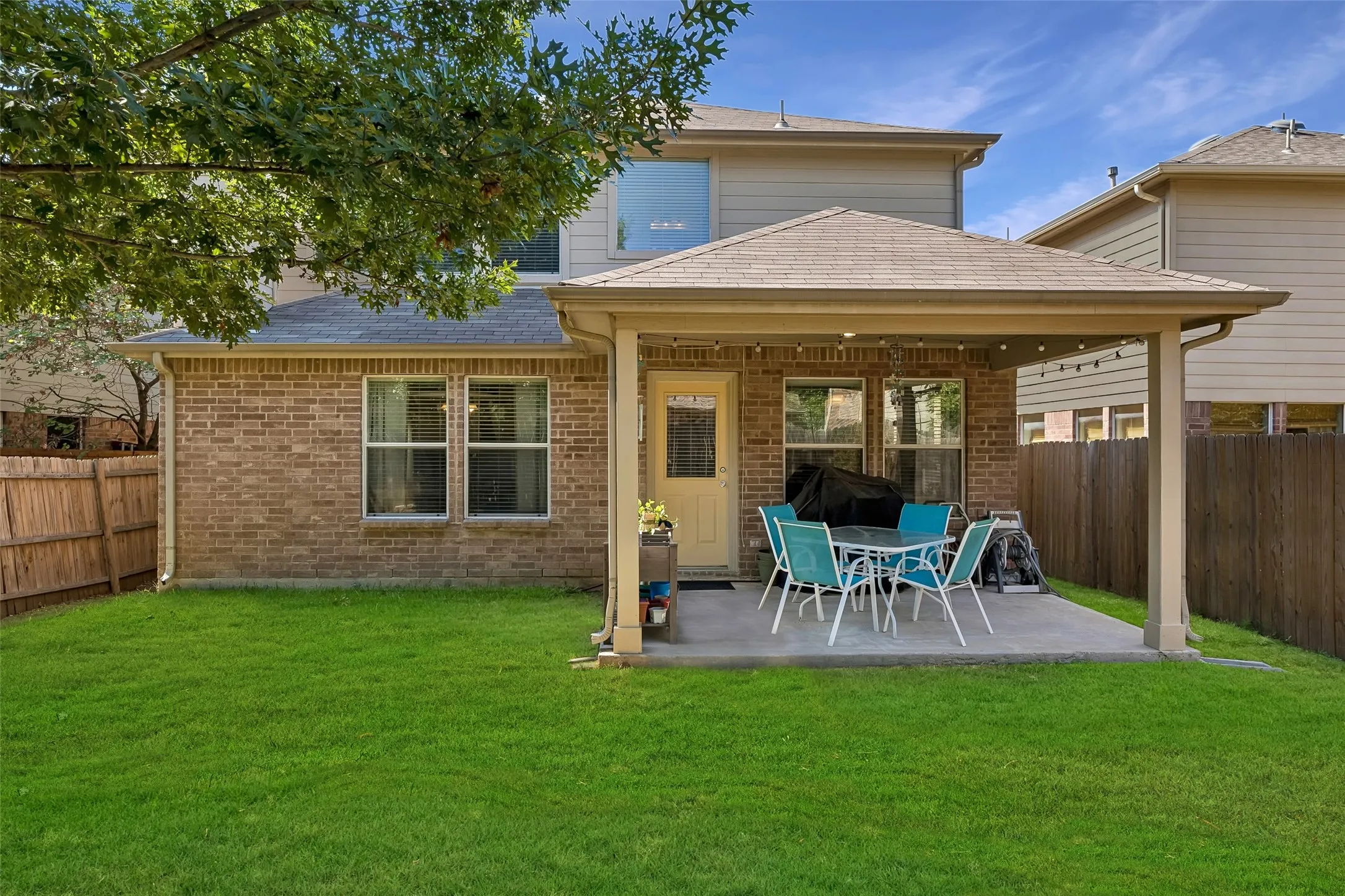 Expansive green lawn with a covered patio featuring a concrete surface