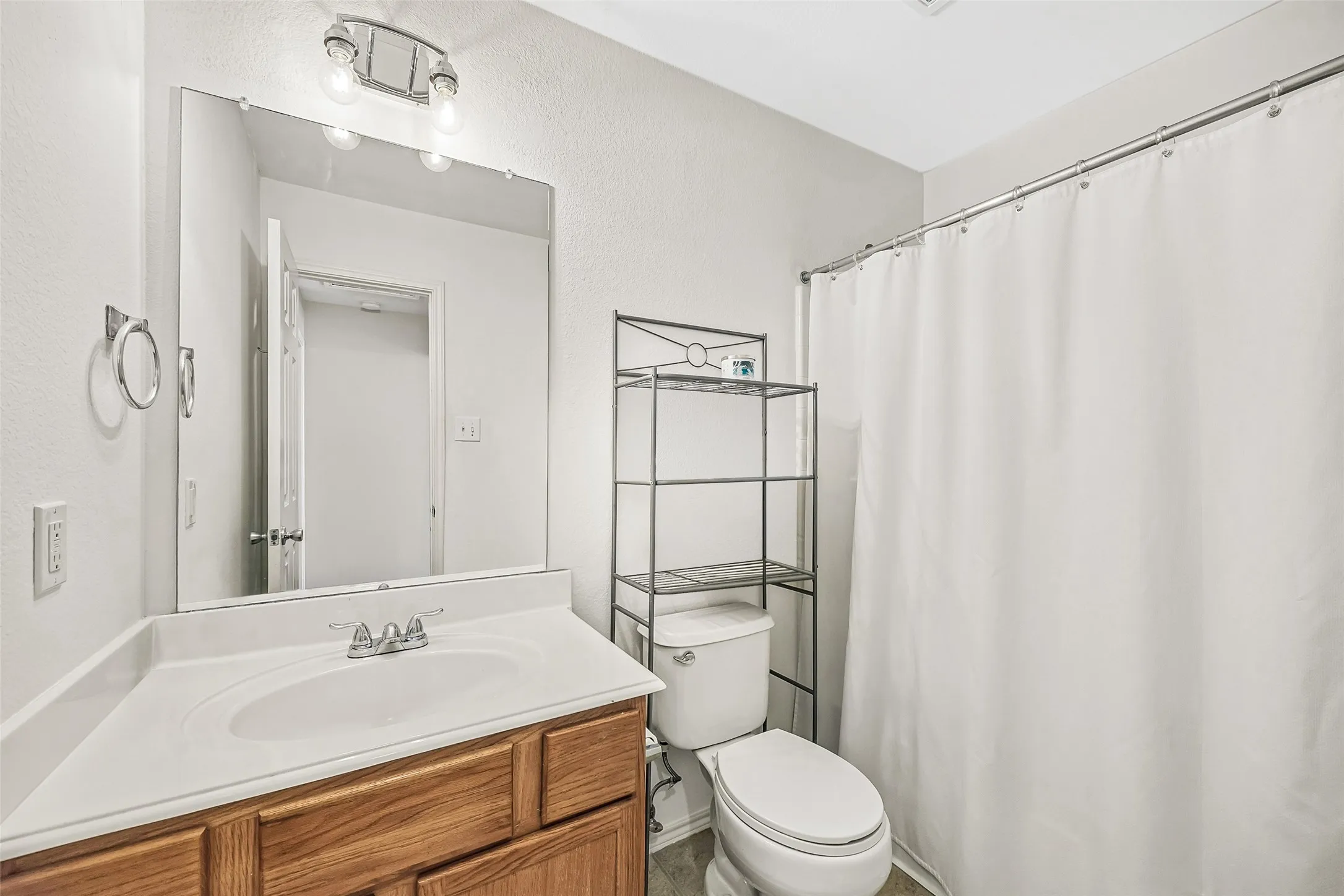 Bathroom featuring a white toilet, chrome fixtures, and a vanity with wood-finish cabinetry and an integrated sink