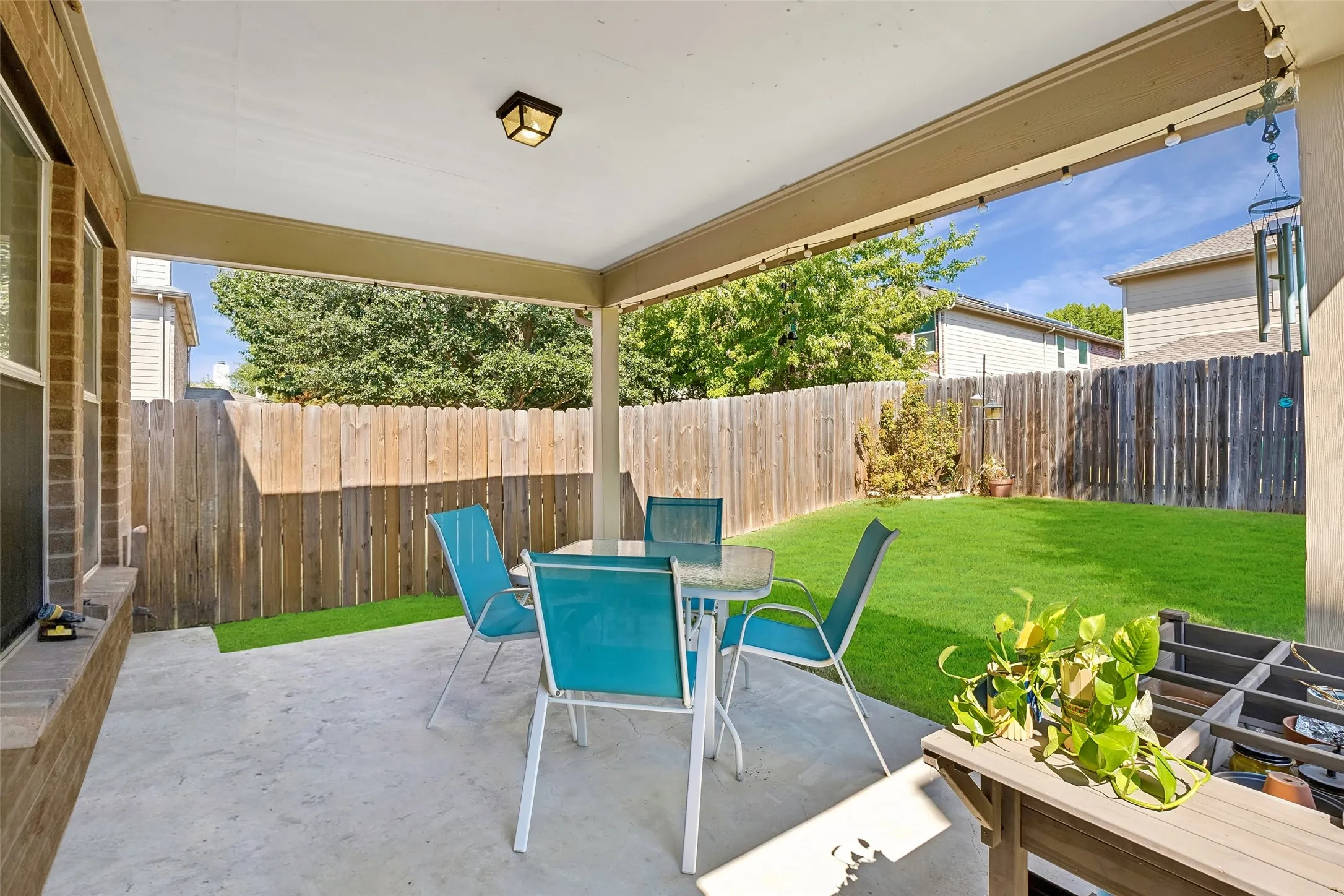 Covered patio with concrete flooring, wood privacy fence, and a manicured lawn