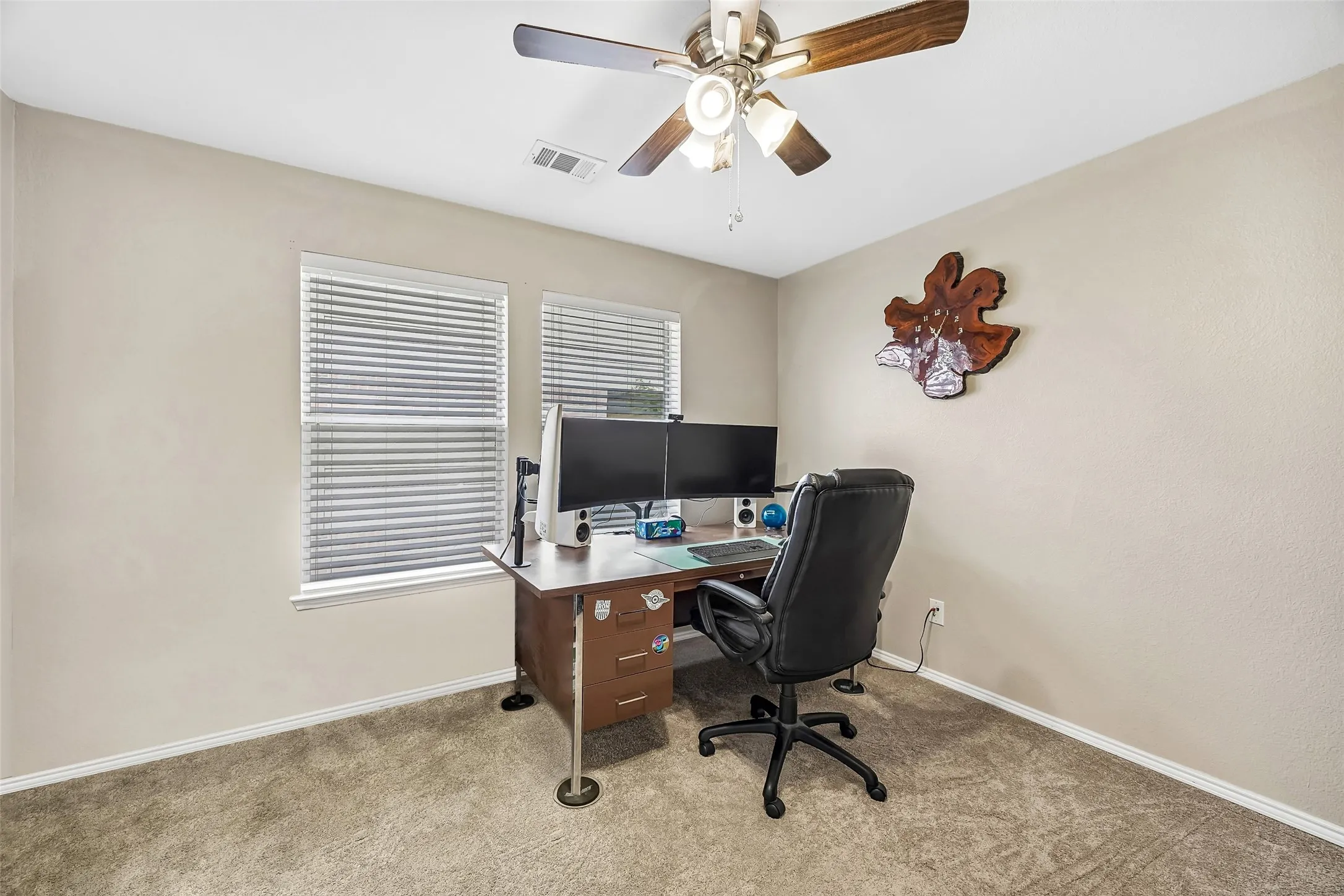 Carpeted room with two windows, horizontal blinds, and a ceiling fan with light fixture