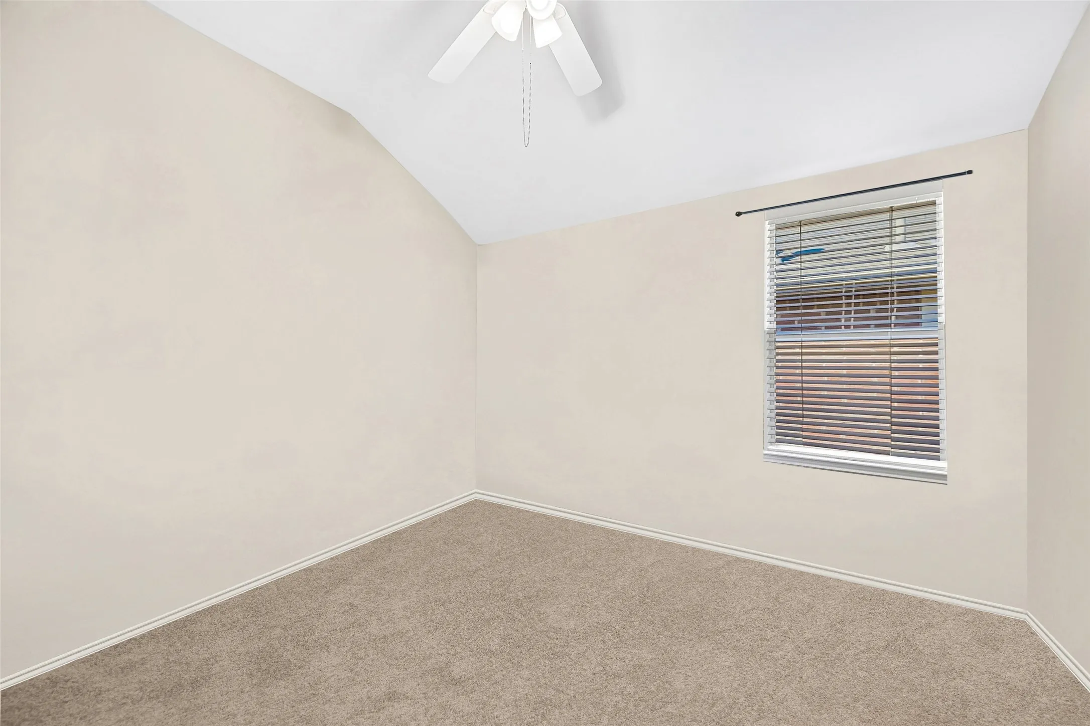 Vaulted ceiling with a ceiling fan, carpeted flooring, and a single window with blinds