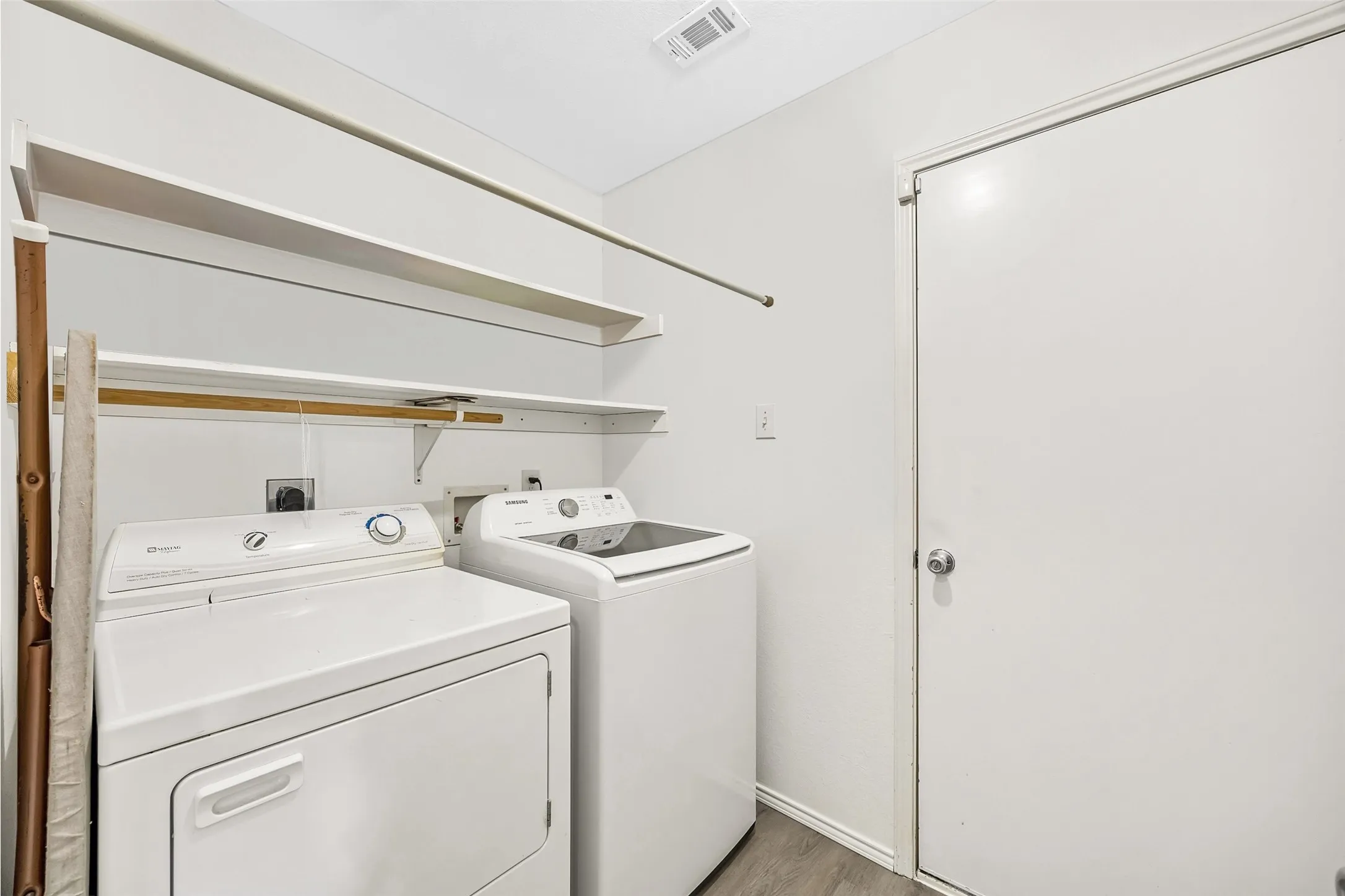 Dedicated utility area featuring a top-load washing machine, front-load dryer, and wall-mounted shelving