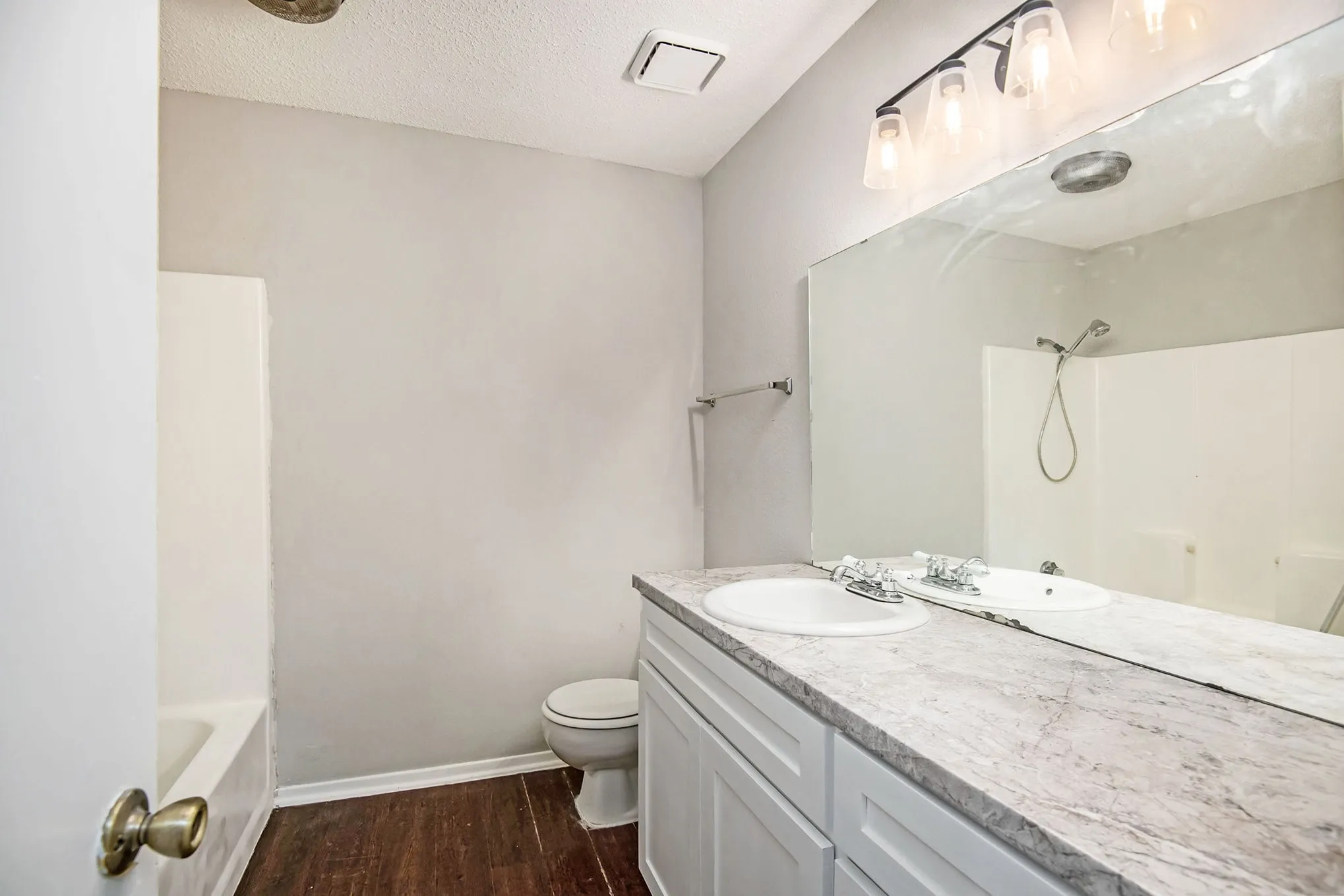 Bathroom featuring a dual vanity with a patterned countertop, white cabinetry, and a full-width wall mirror