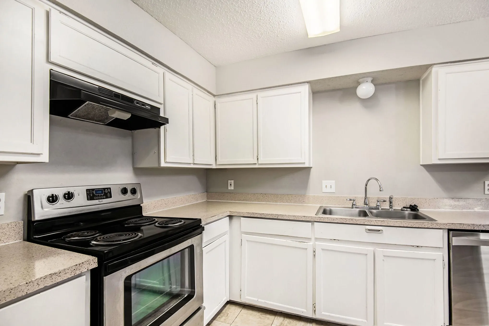 Kitchen featuring white cabinetry, light-toned countertops, a stainless steel electric range, and a double basin sink