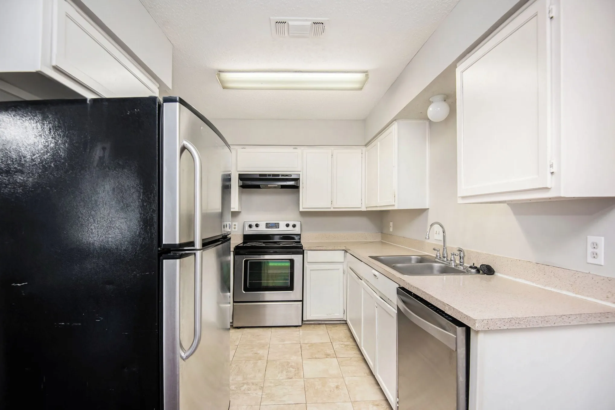 Kitchen featuring white cabinetry, tile flooring, stainless steel appliances, and a double basin sink