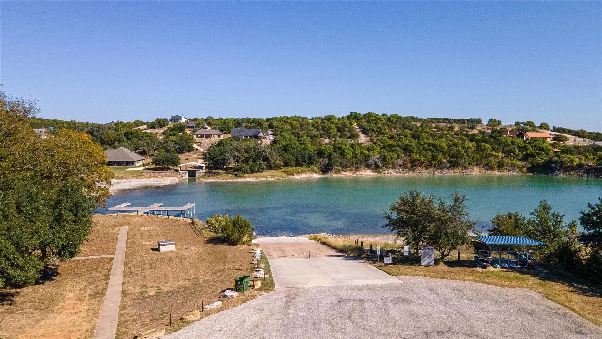 Expansive water frontage with multiple docks, a concrete boat ramp, and a covered lakeside structure