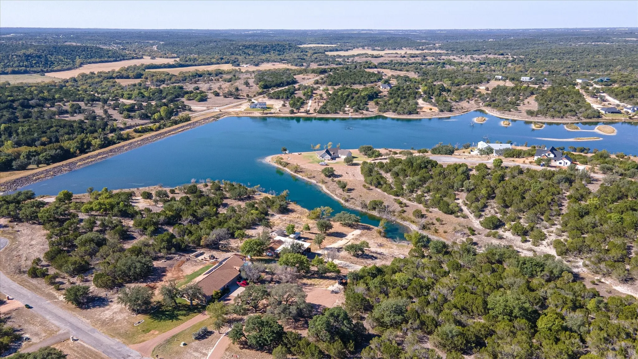 Expansive body of water with surrounding verdant trees and clear skies