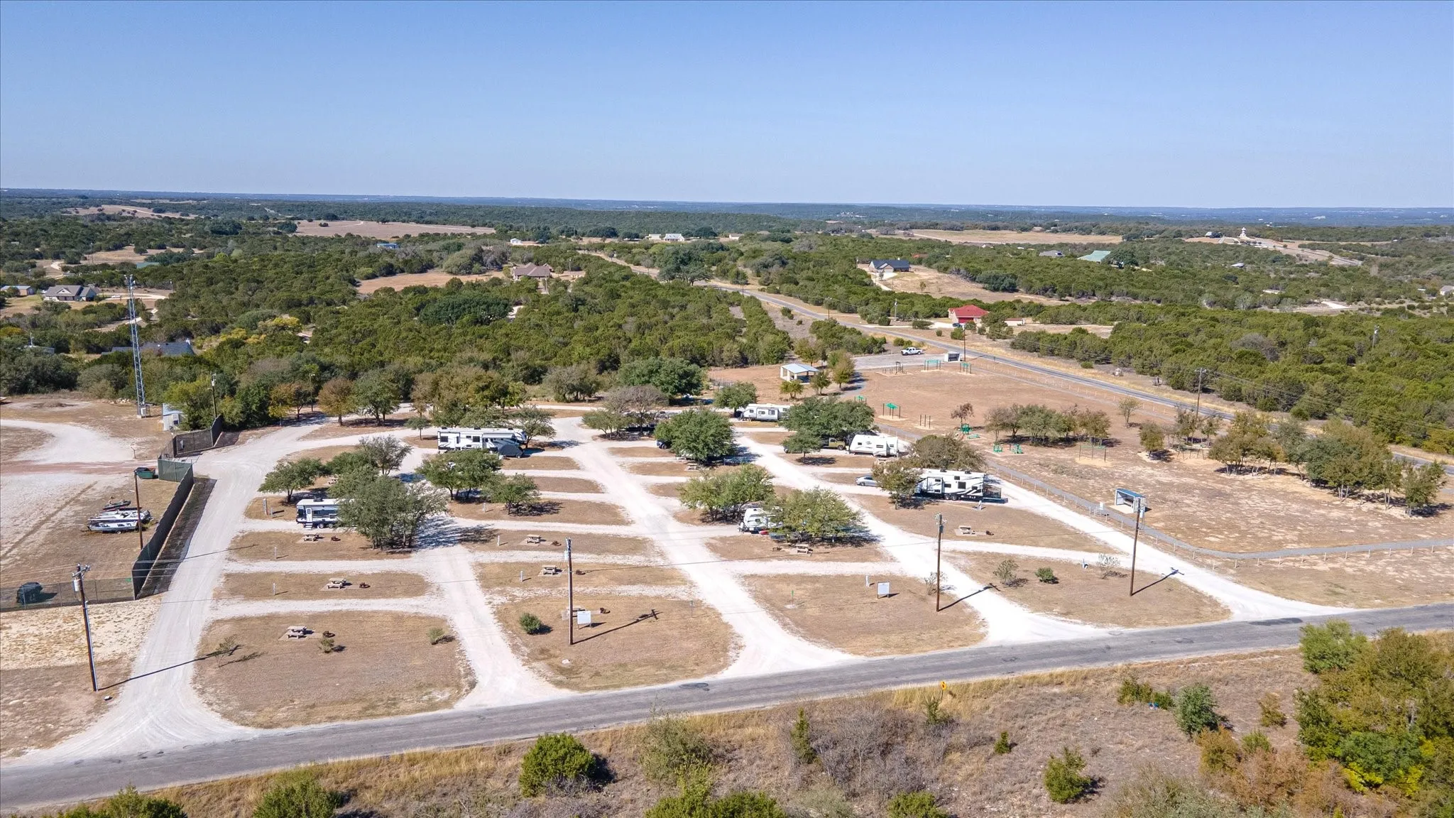 RV park with multiple gravel pads, individual utility hookups, and mature trees