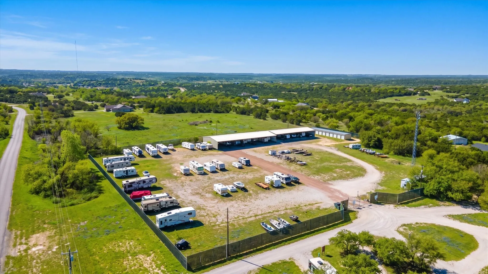 Extensive property featuring multiple storage buildings, a paved access road, and a fenced perimeter