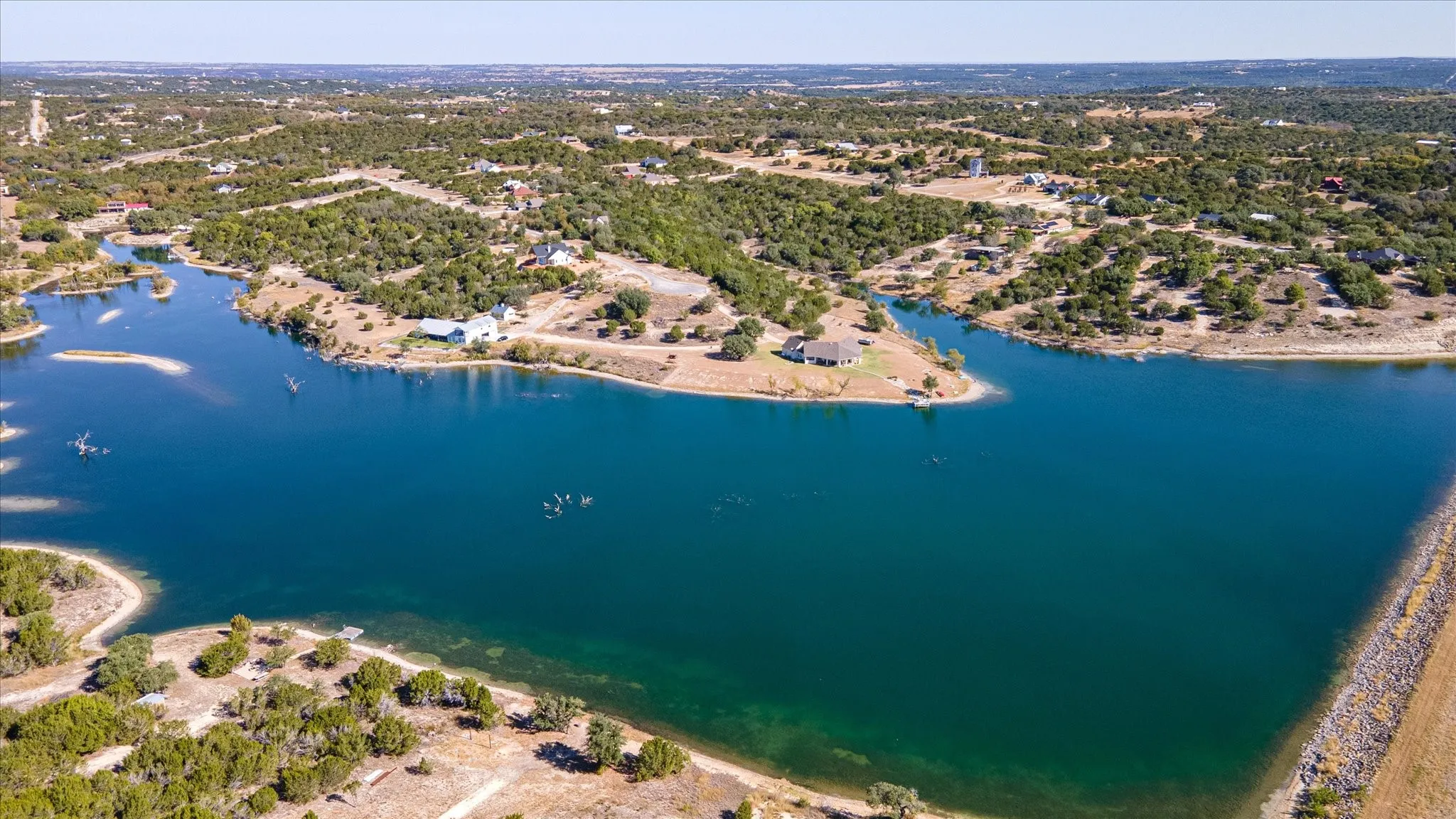 Expansive waterfront property featuring mature trees and established residences along the shore
