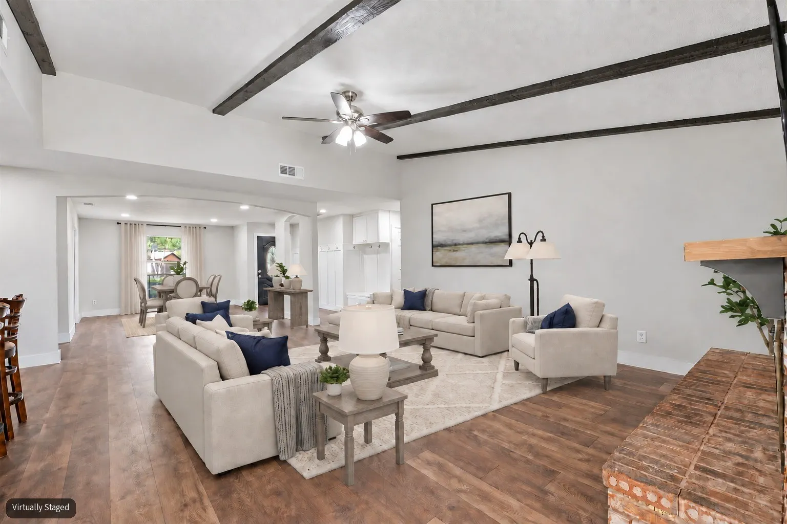 Virtually staged living room with vaulted ceilings and wood beams.