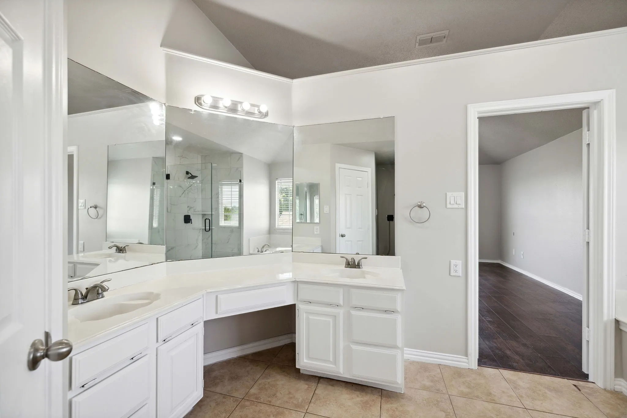 Bathroom with vanity with extensive cabinet space, walk in shower, tile flooring, vaulted ceiling, and dual sinks