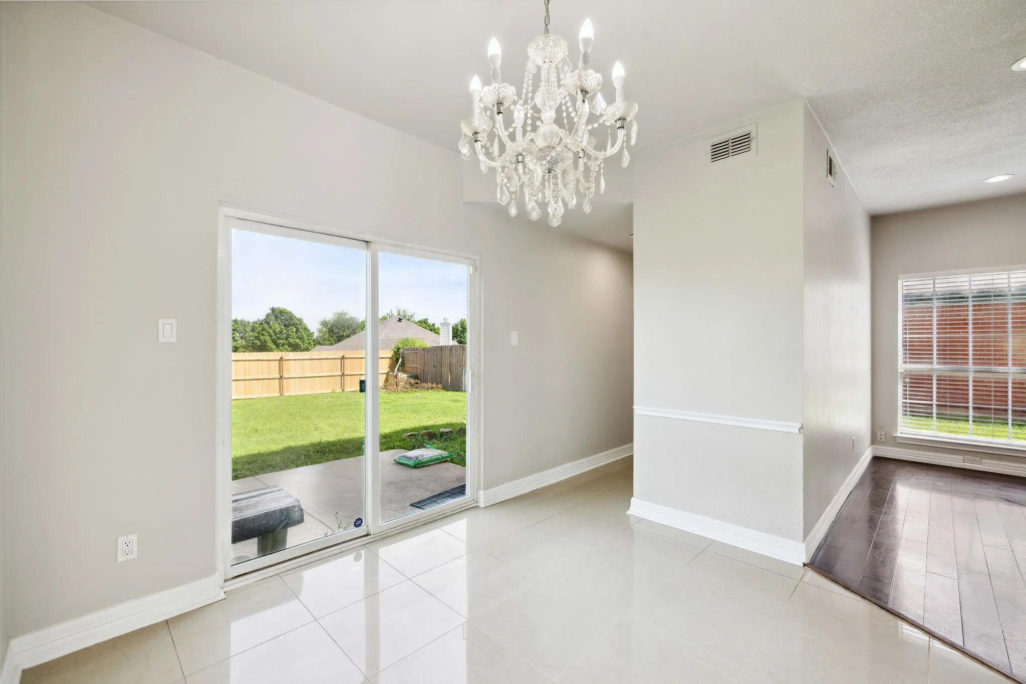 Unfurnished room with plenty of natural light, a notable chandelier, and light tile flooring