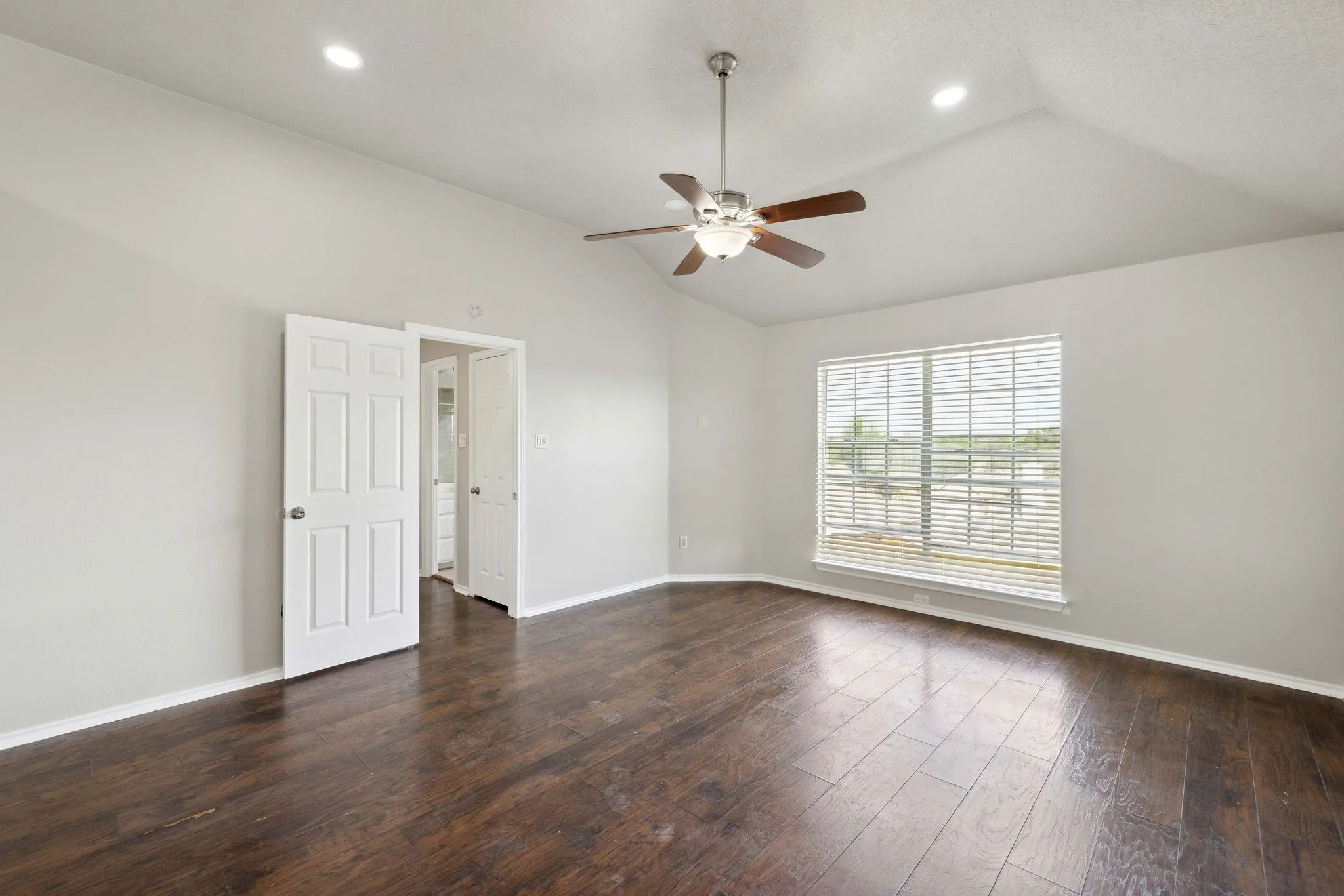 Spare room with dark wood-type flooring, ceiling fan, and lofted ceiling