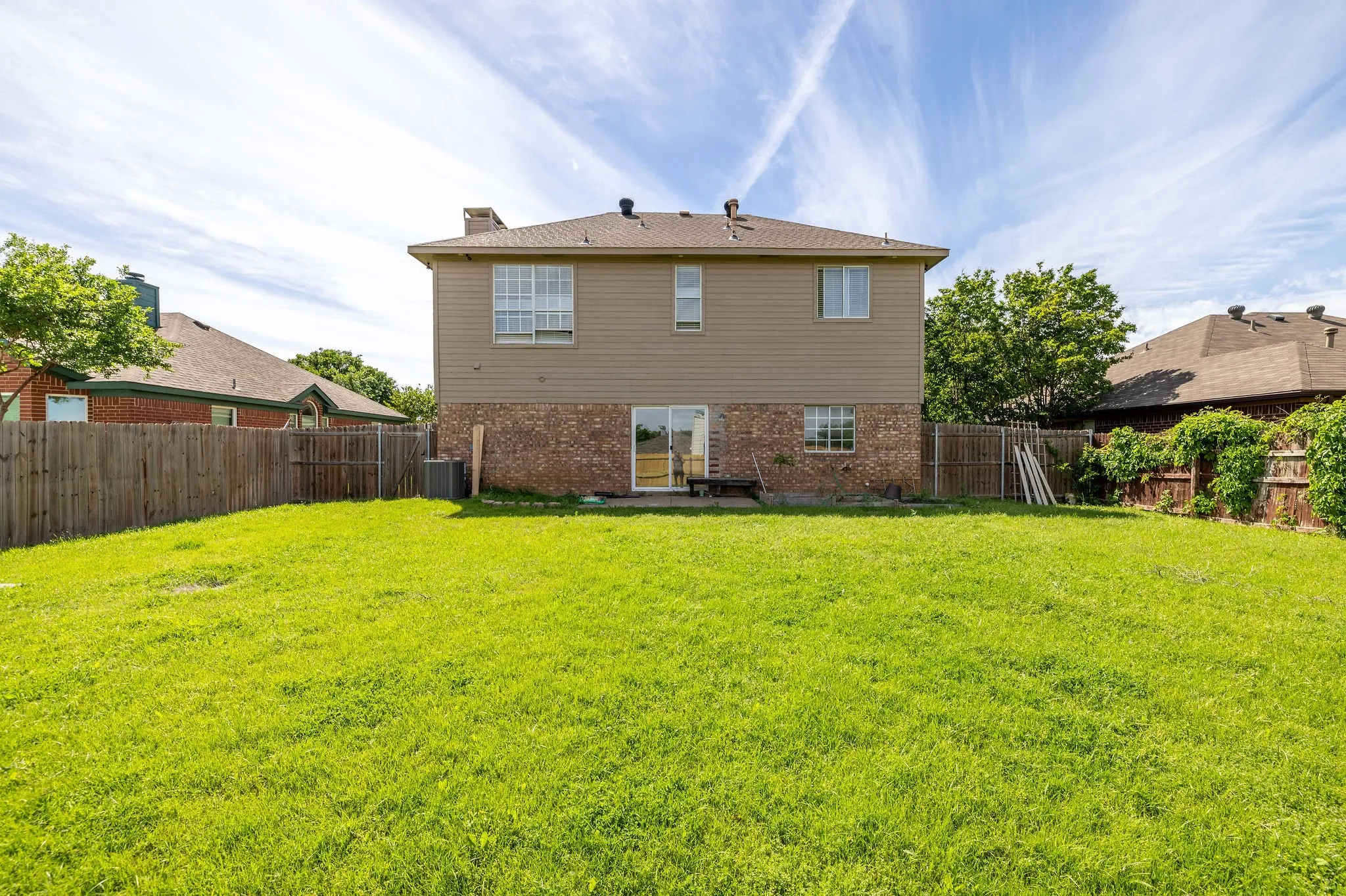 Back of property with central AC and a lawn