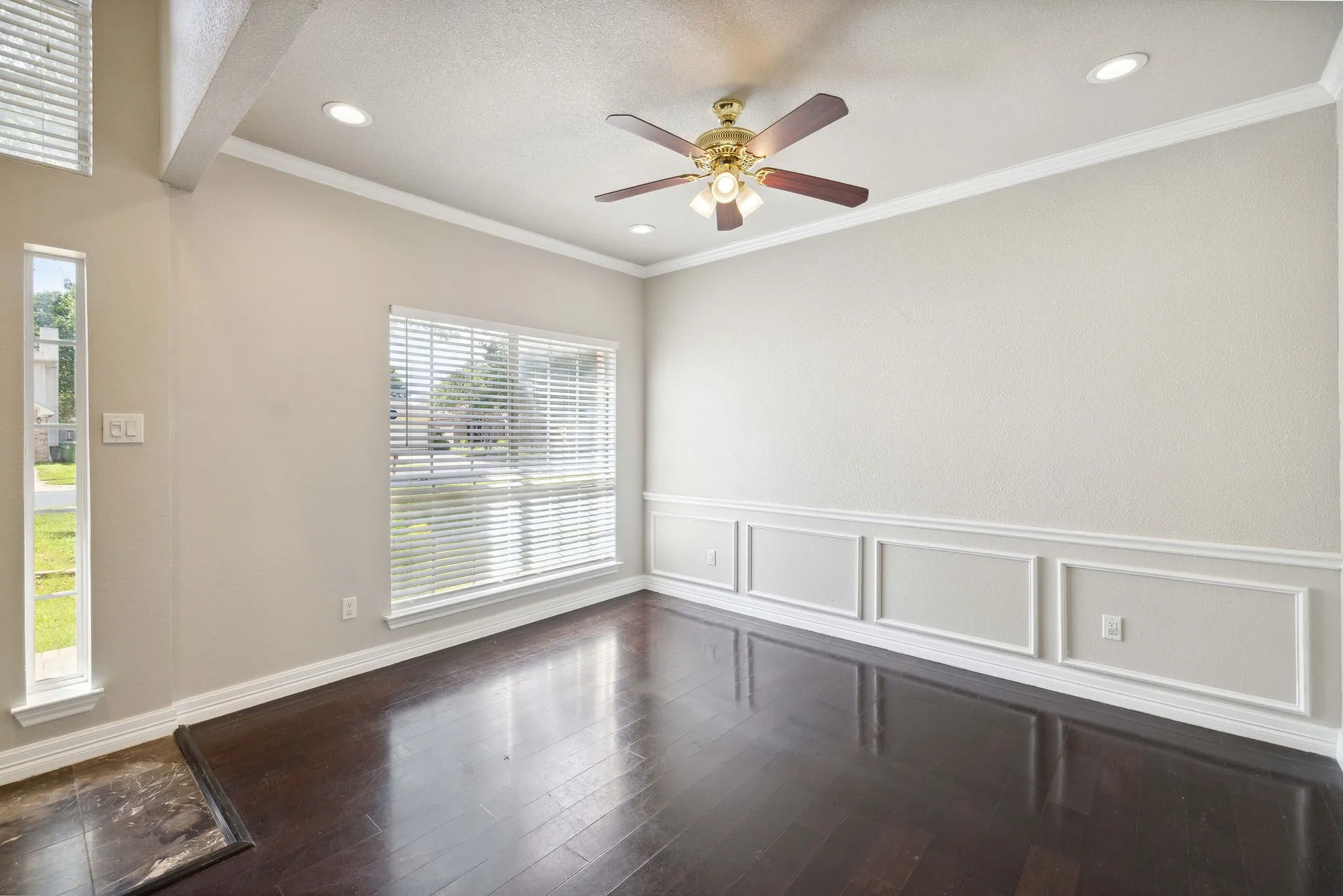 Spare room featuring plenty of natural light, crown molding, dark wood-type flooring, and ceiling fan