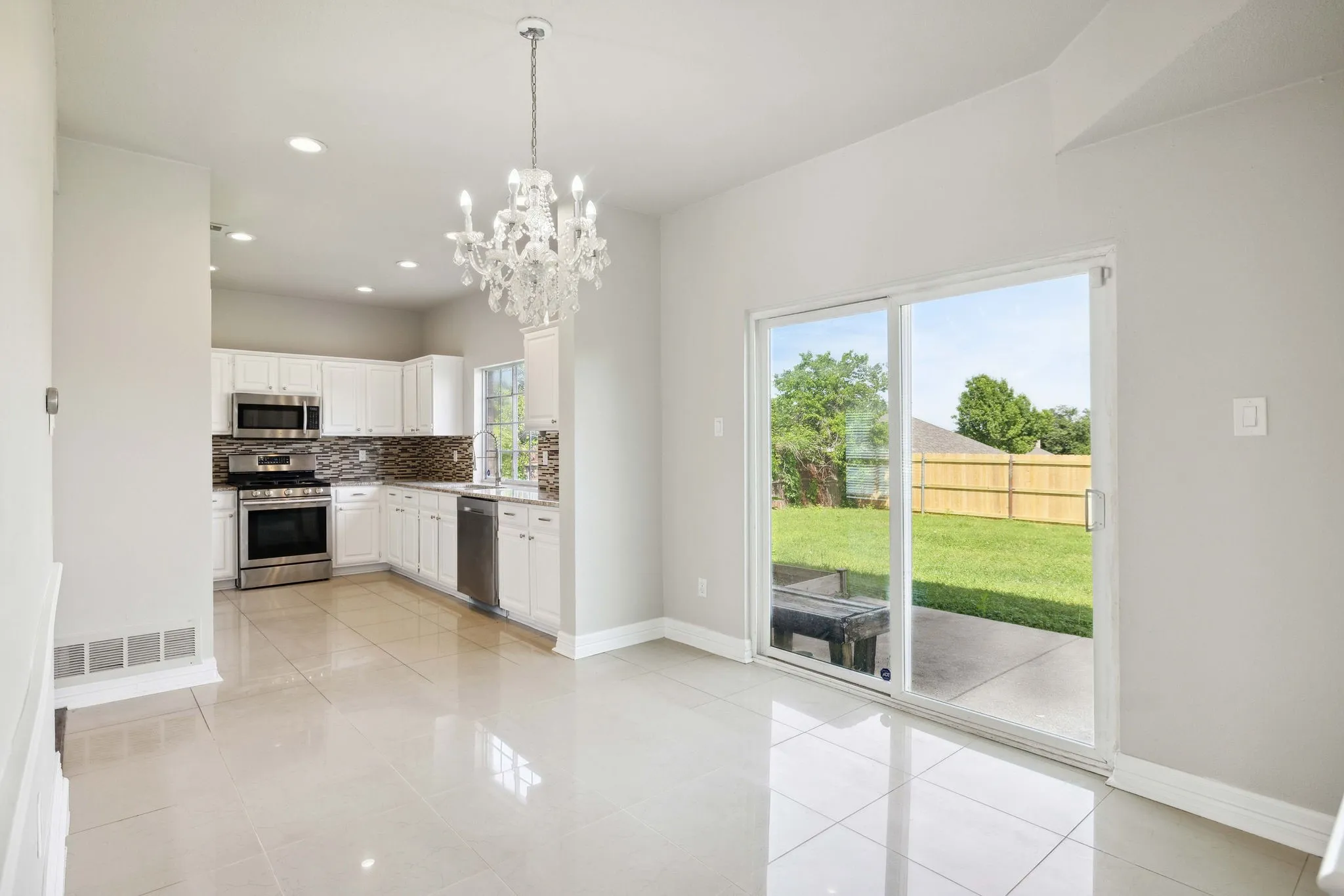 Kitchen featuring tasteful backsplash, appliances with stainless steel finishes, white cabinets, and light tile floors