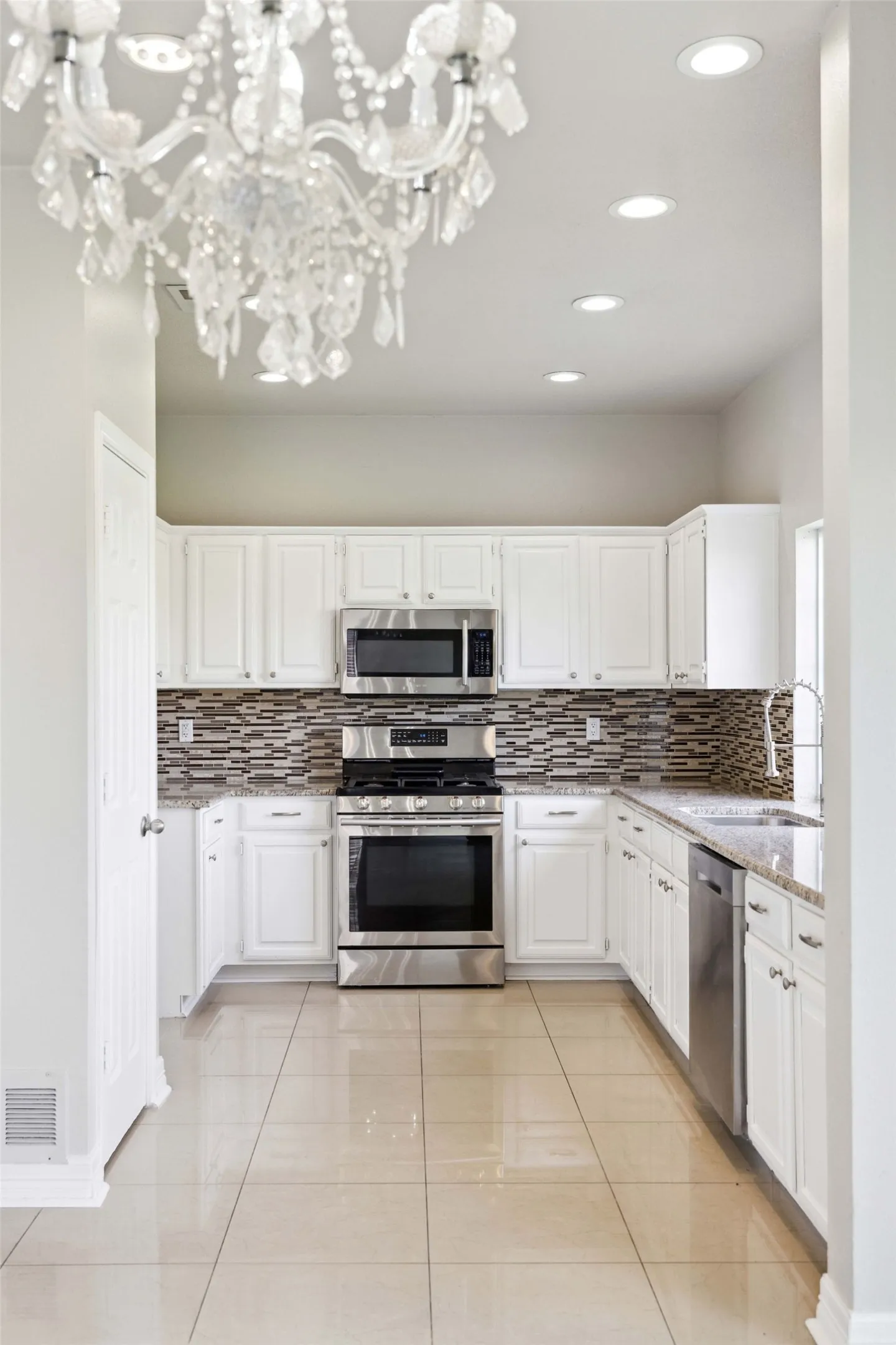 Kitchen featuring backsplash, stainless steel appliances, and white cabinetry