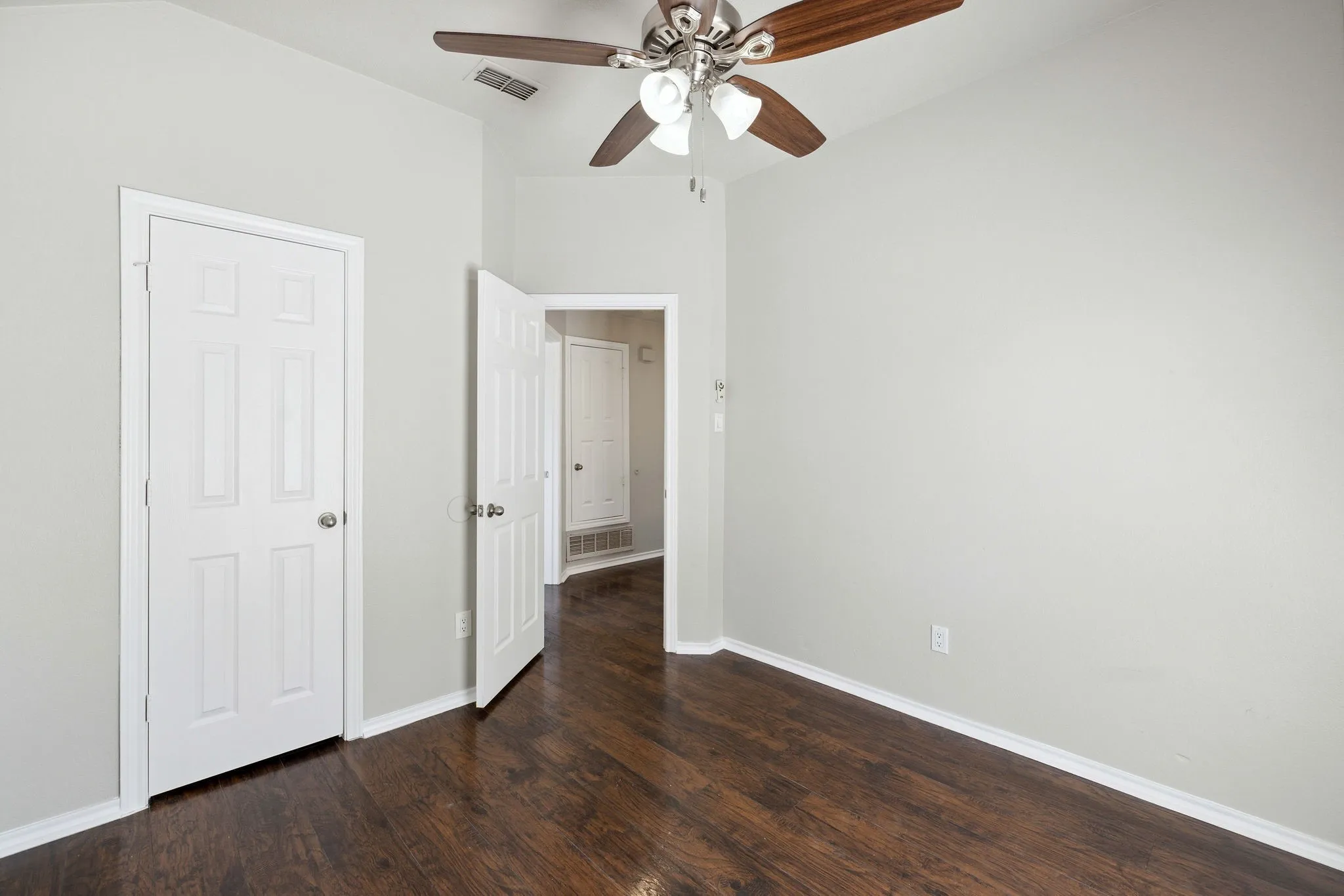 Unfurnished bedroom featuring dark hardwood / wood-style flooring and ceiling fan