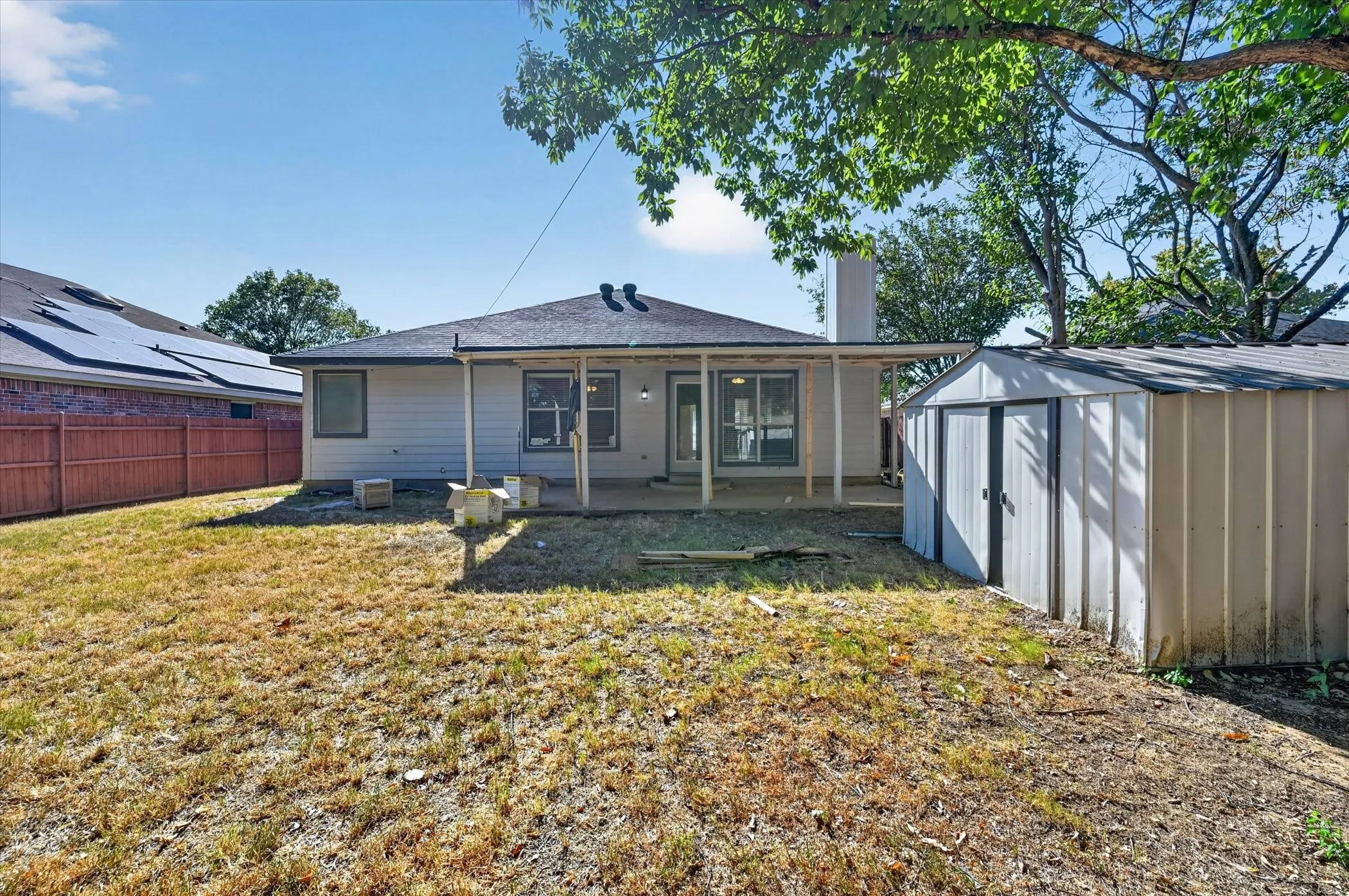 Expansive backyard featuring a covered patio, a storage shed, and a privacy fence