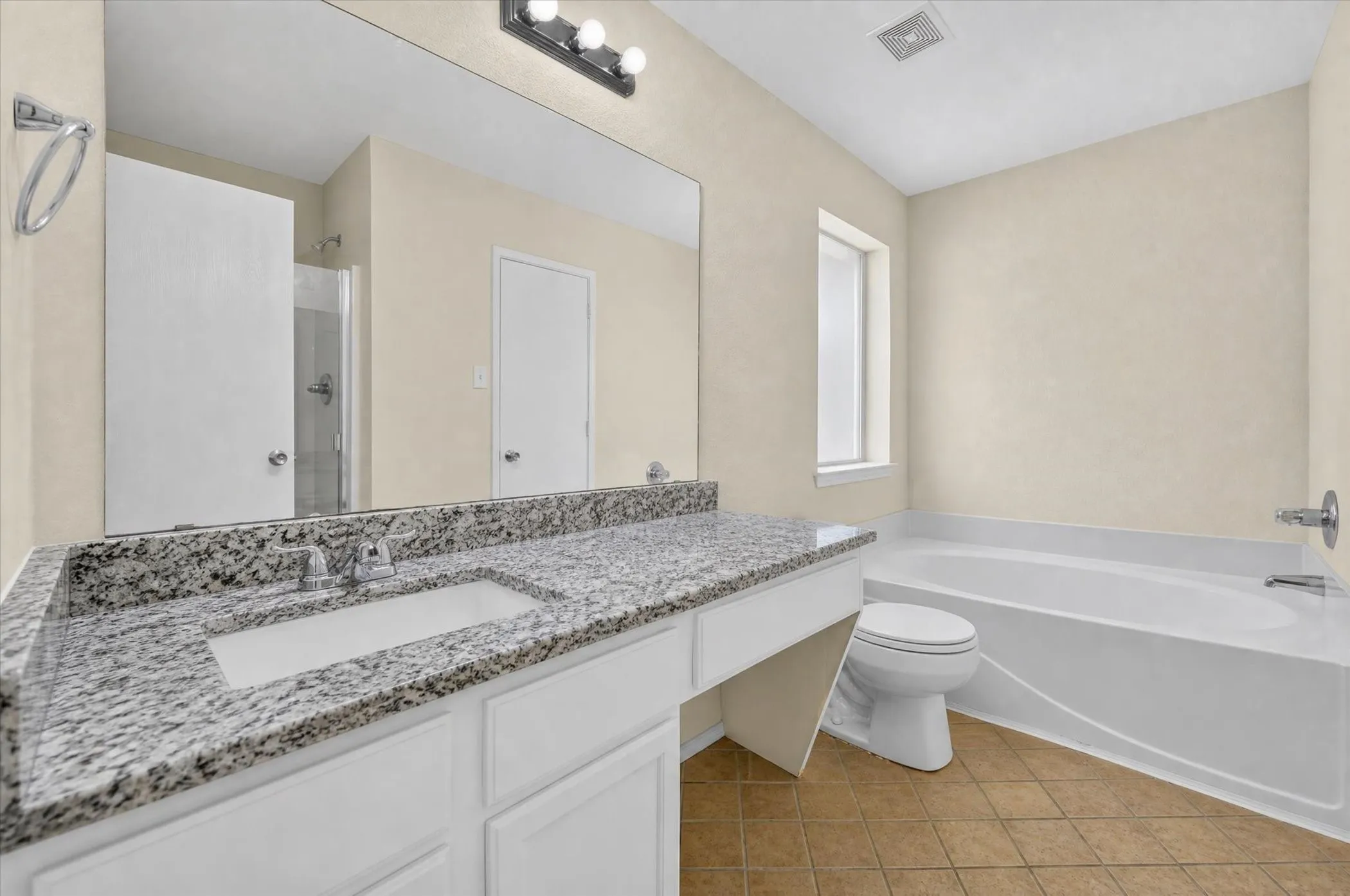 Double vanity with granite countertop, integrated sink, and white cabinetry