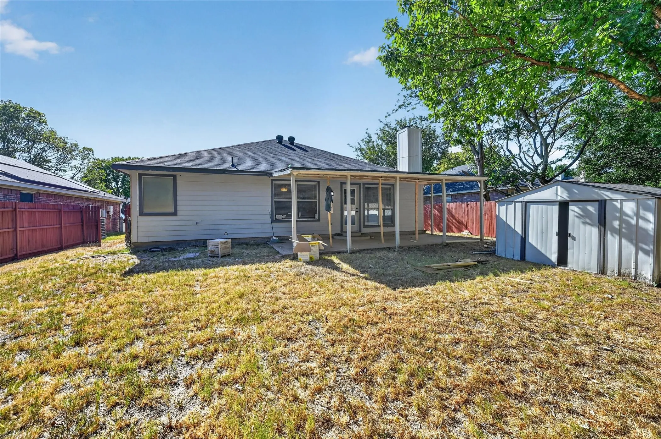 Expansive backyard featuring a covered patio, a storage shed, and a privacy fence