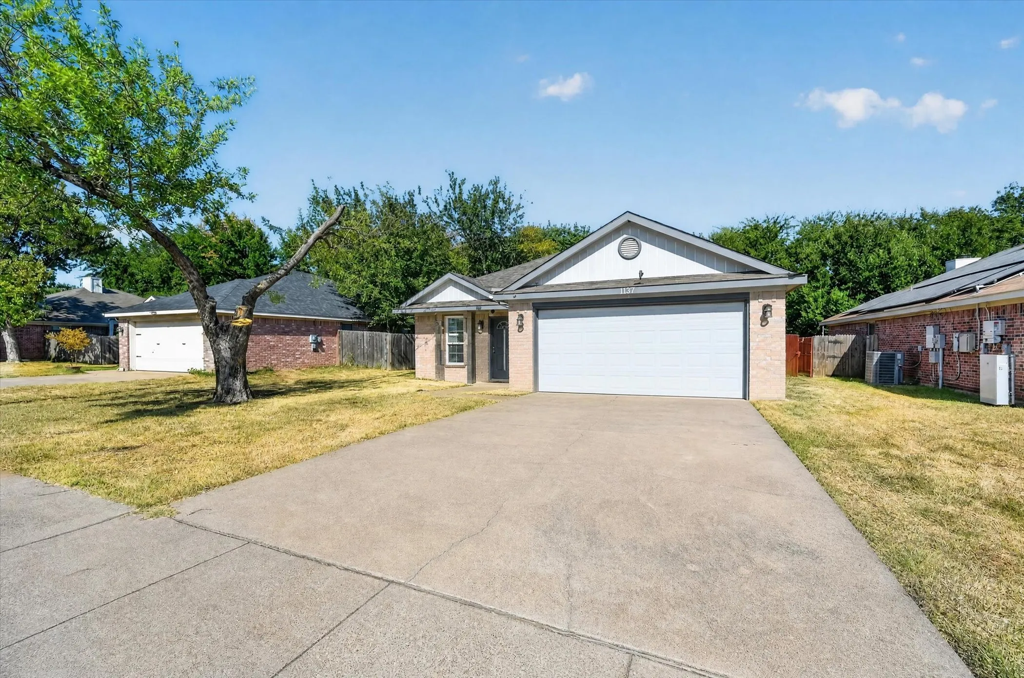 Single-story residence featuring a two-car garage, concrete driveway, and a partially brick exterior