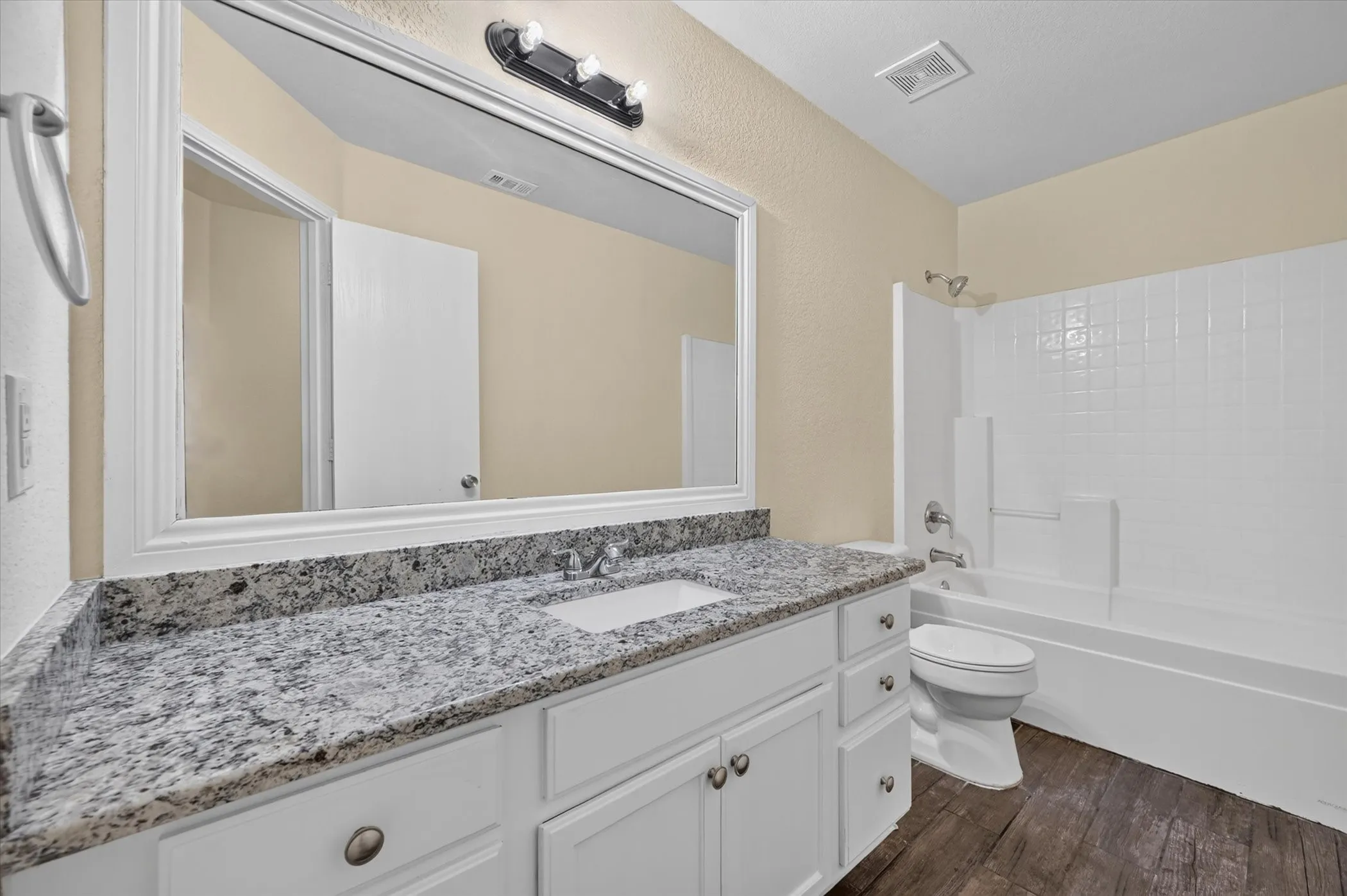 Vanity with a speckled countertop, integrated sink, and white cabinetry