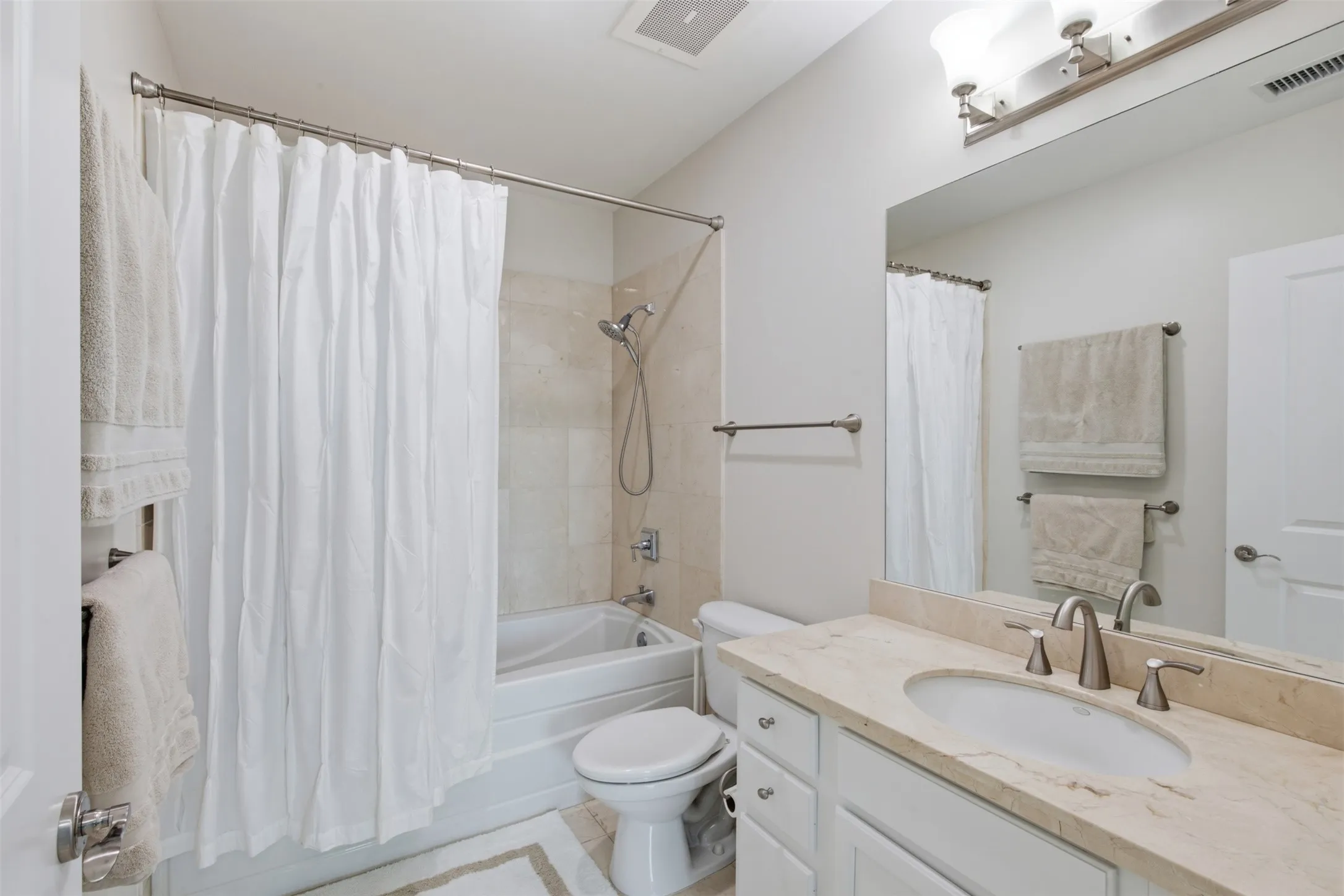 Bath #1 Ensuite to Bedroom   Bathtub with tiled surround, single vanity with light-toned countertop, undermount sink, and brushed nickel fixtures
