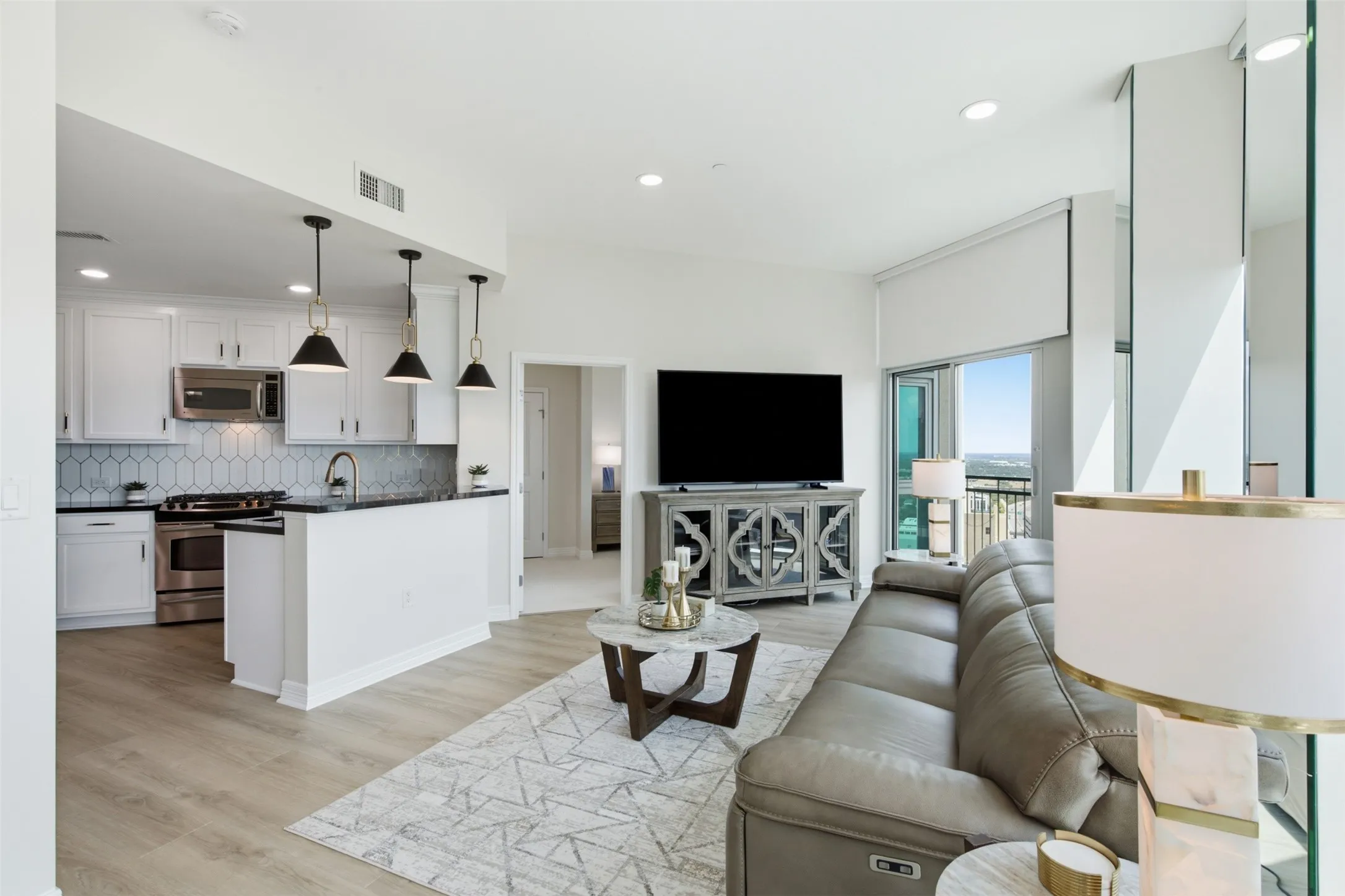 Open-concept living space with wood-finish flooring, recessed lighting, and a private balcony