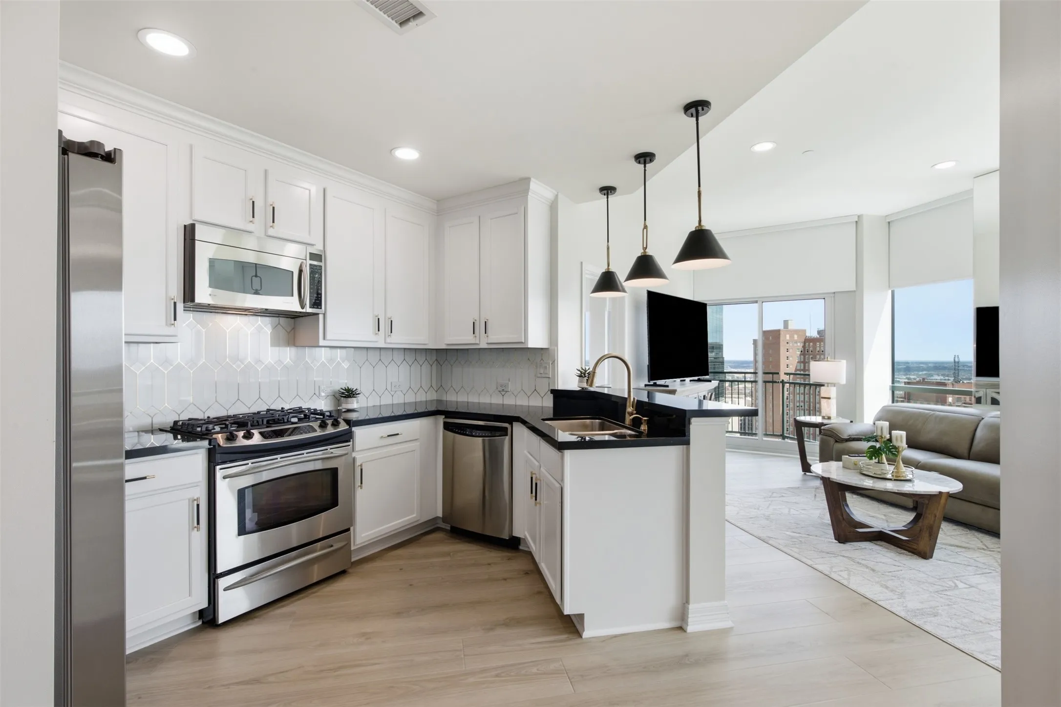 Kitchen featuring white cabinetry, stainless steel appliances, a geometric tile backsplash, and dark countertops