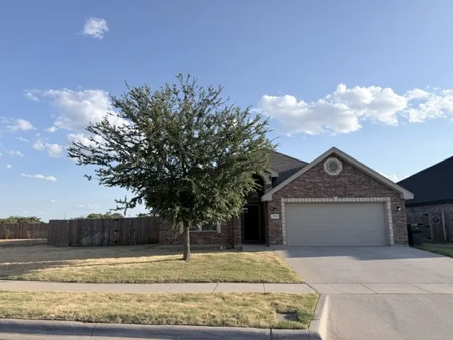 Brick exterior with a gabled roofline, attached garage, and concrete driveway