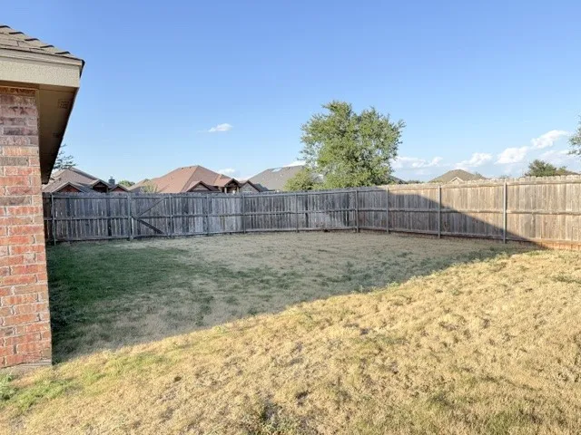 Fenced backyard featuring a wood privacy fence and a brick exterior wall