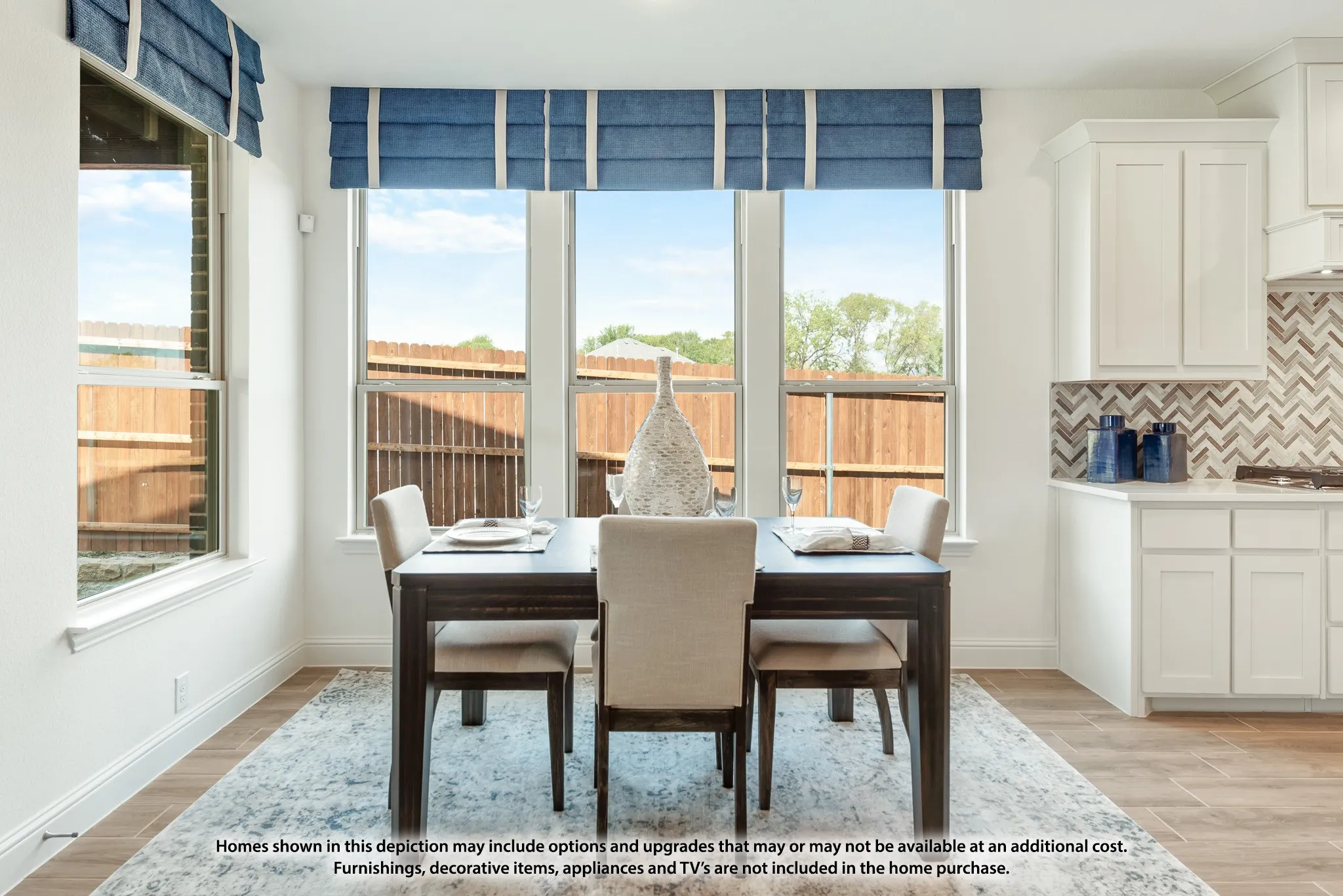 Wood-finish flooring, white cabinetry, a chevron-patterned tile backsplash, and multiple windows