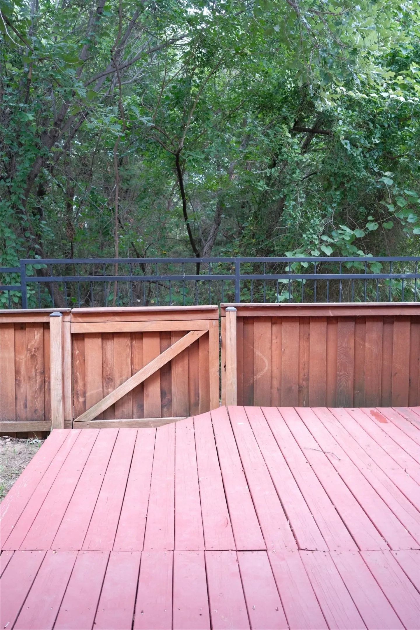 Wood deck featuring a privacy fence and gate, with a metal railing