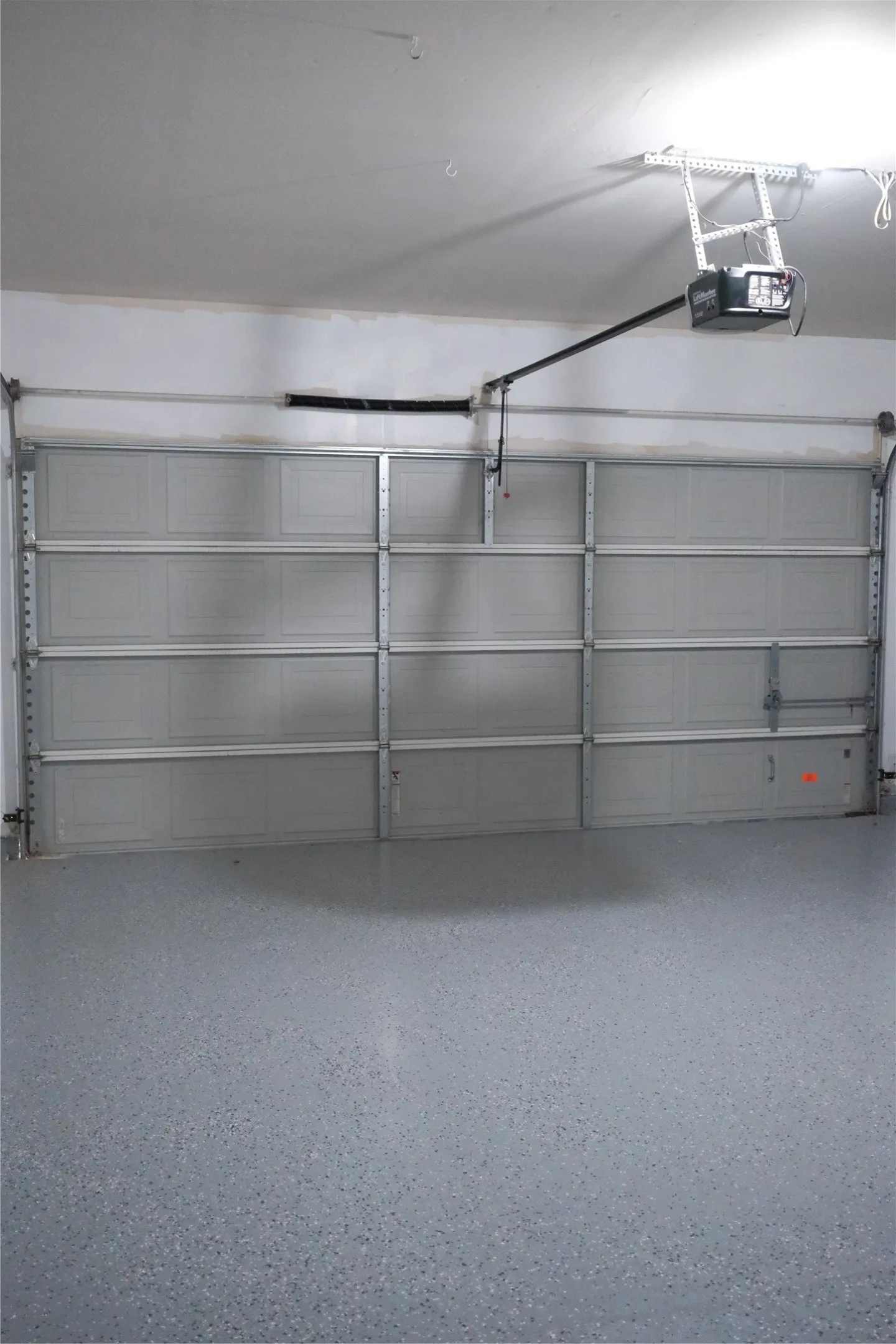 Spacious garage featuring dual panel doors with frosted glass inserts, epoxy-coated flooring, and an automatic overhead door opener system