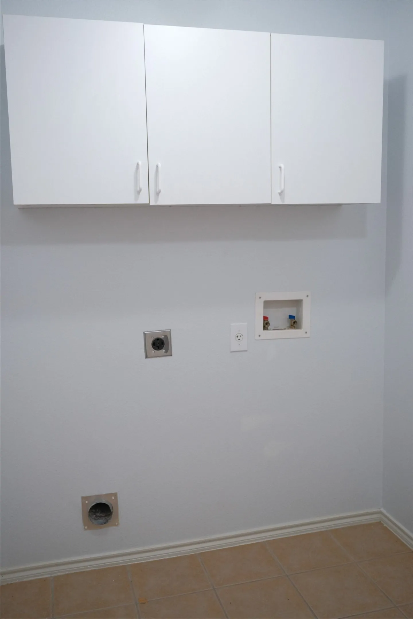 Laundry area featuring white wall cabinetry, tile flooring, and utility hookups