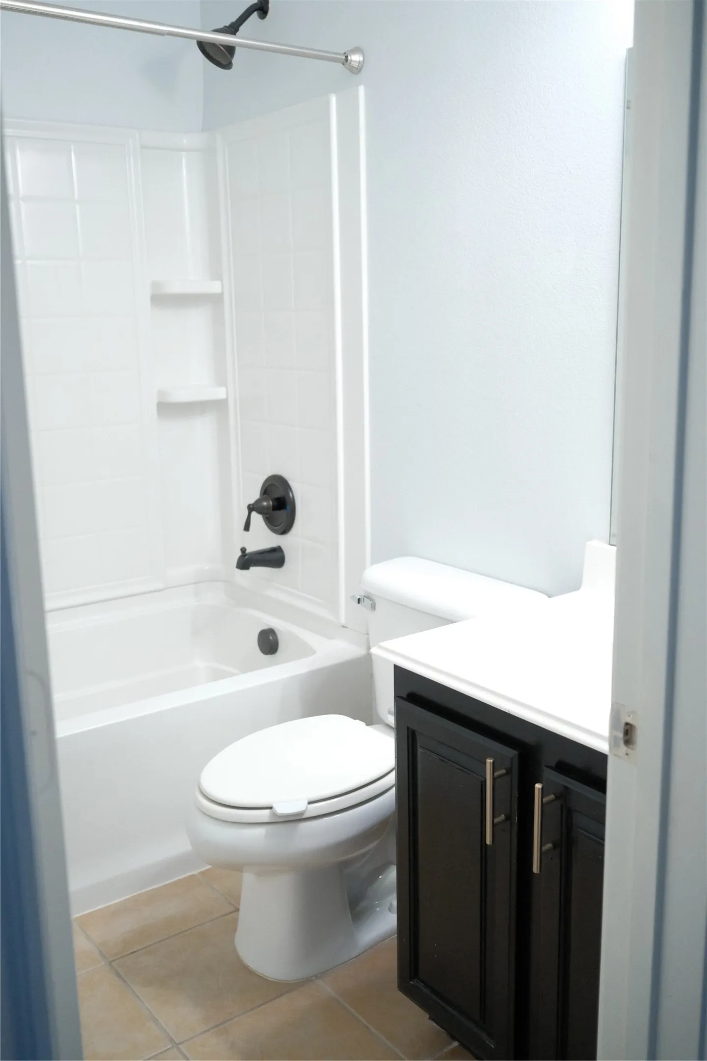 Bathroom with a white tub-shower combination, dark bronze fixtures, a white toilet, a dark wood-finish vanity, and a white countertop