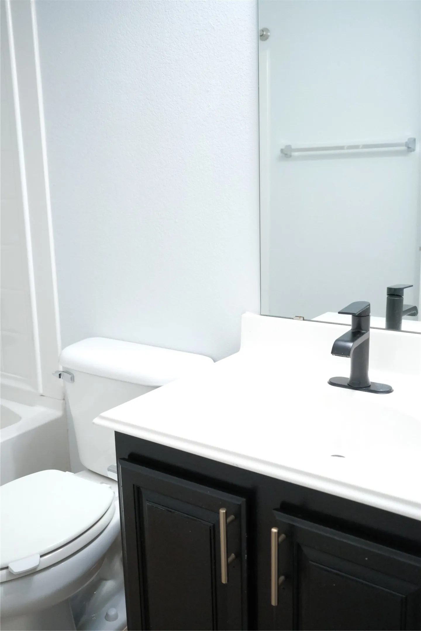 Black vanity with gold-tone hardware, white countertop, integrated sink, and matte black faucet