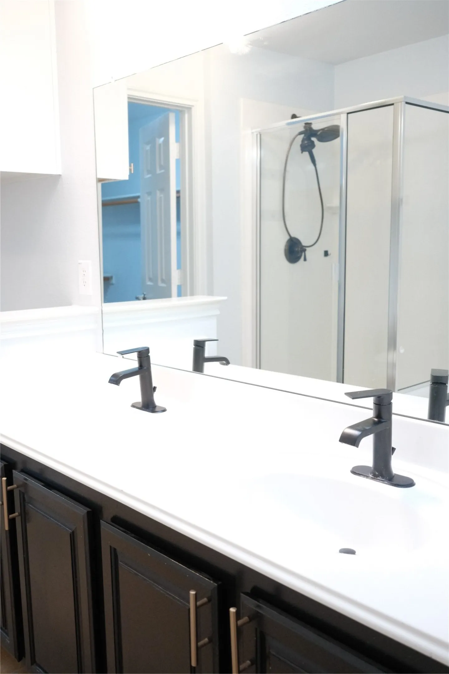 Dual vanity with undermount sinks, matte black faucets, dark cabinetry, and a spacious mirror