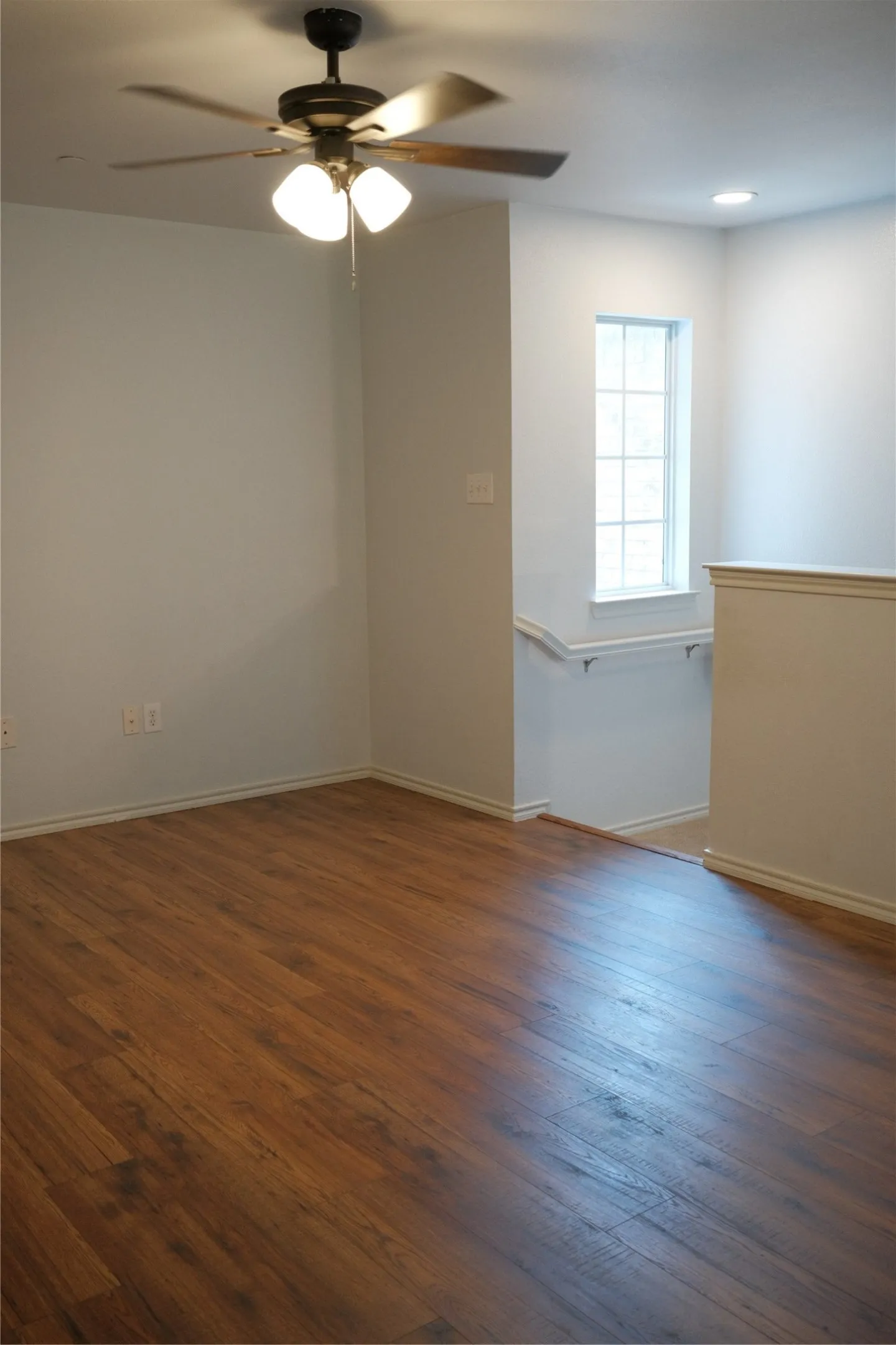 Wood-finish flooring with a ceiling fan light fixture and recessed lighting
