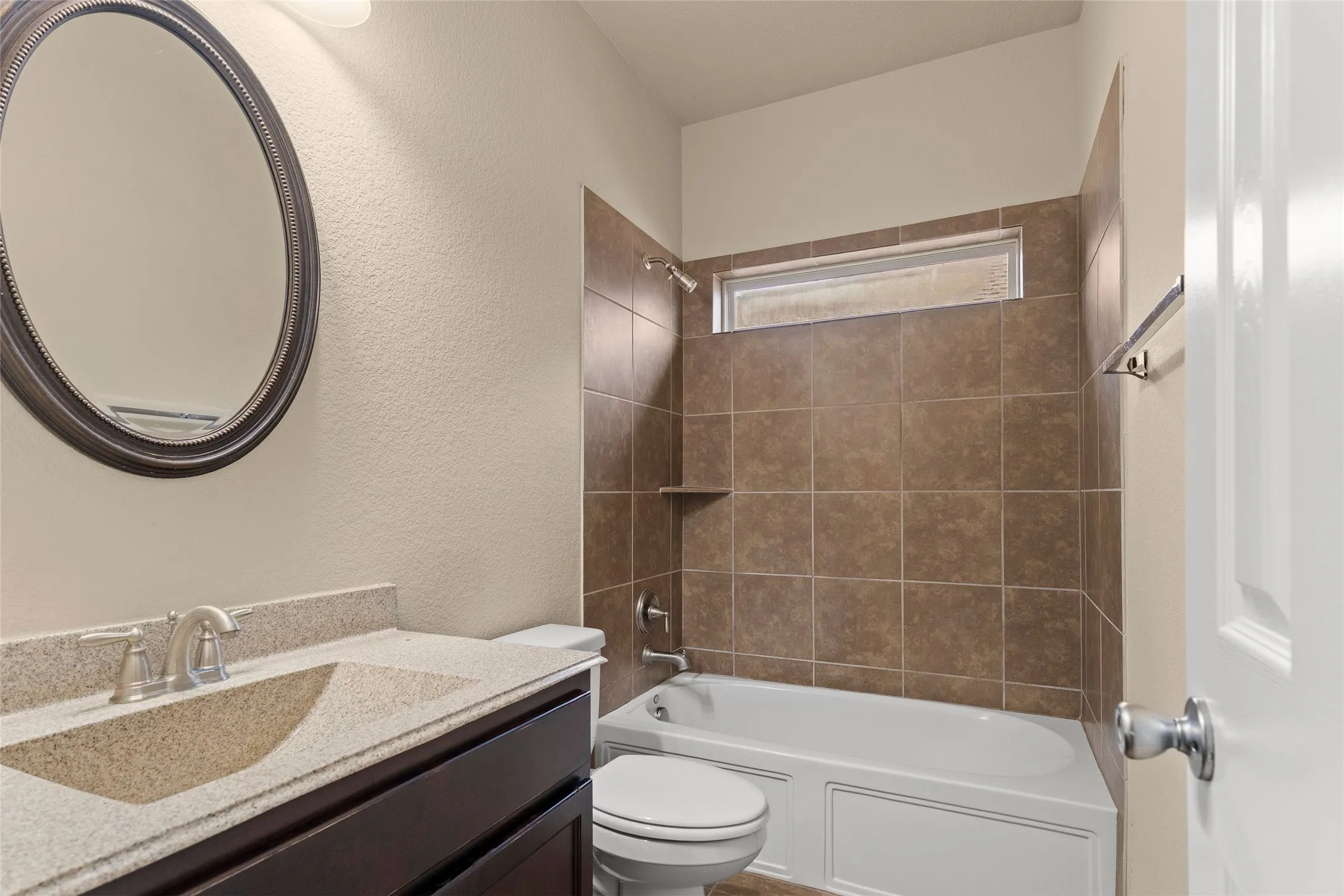 Full bathroom featuring bathtub / shower combination, vanity, and a textured wall