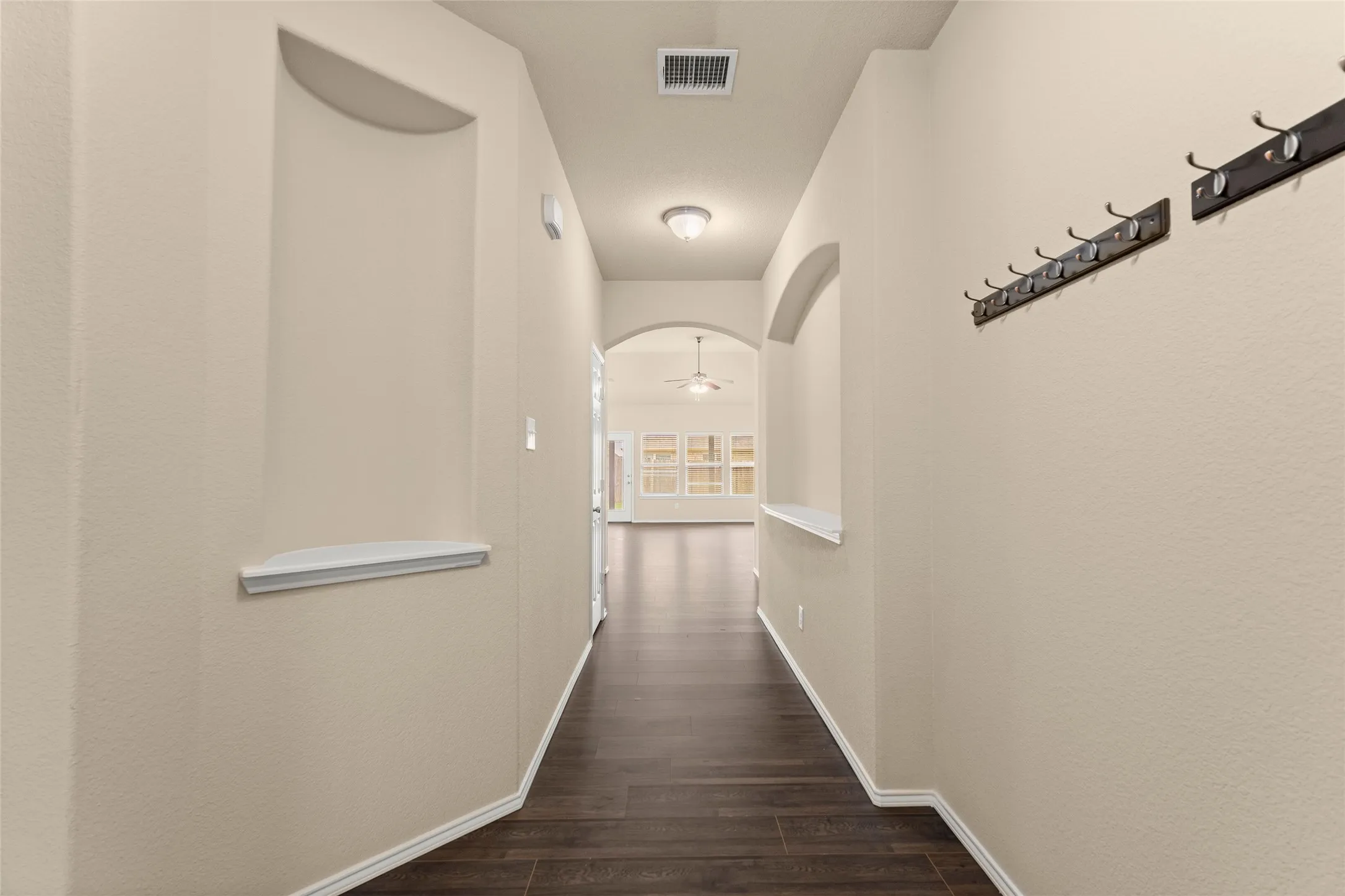 Hall with arched walkways and dark wood-style flooring