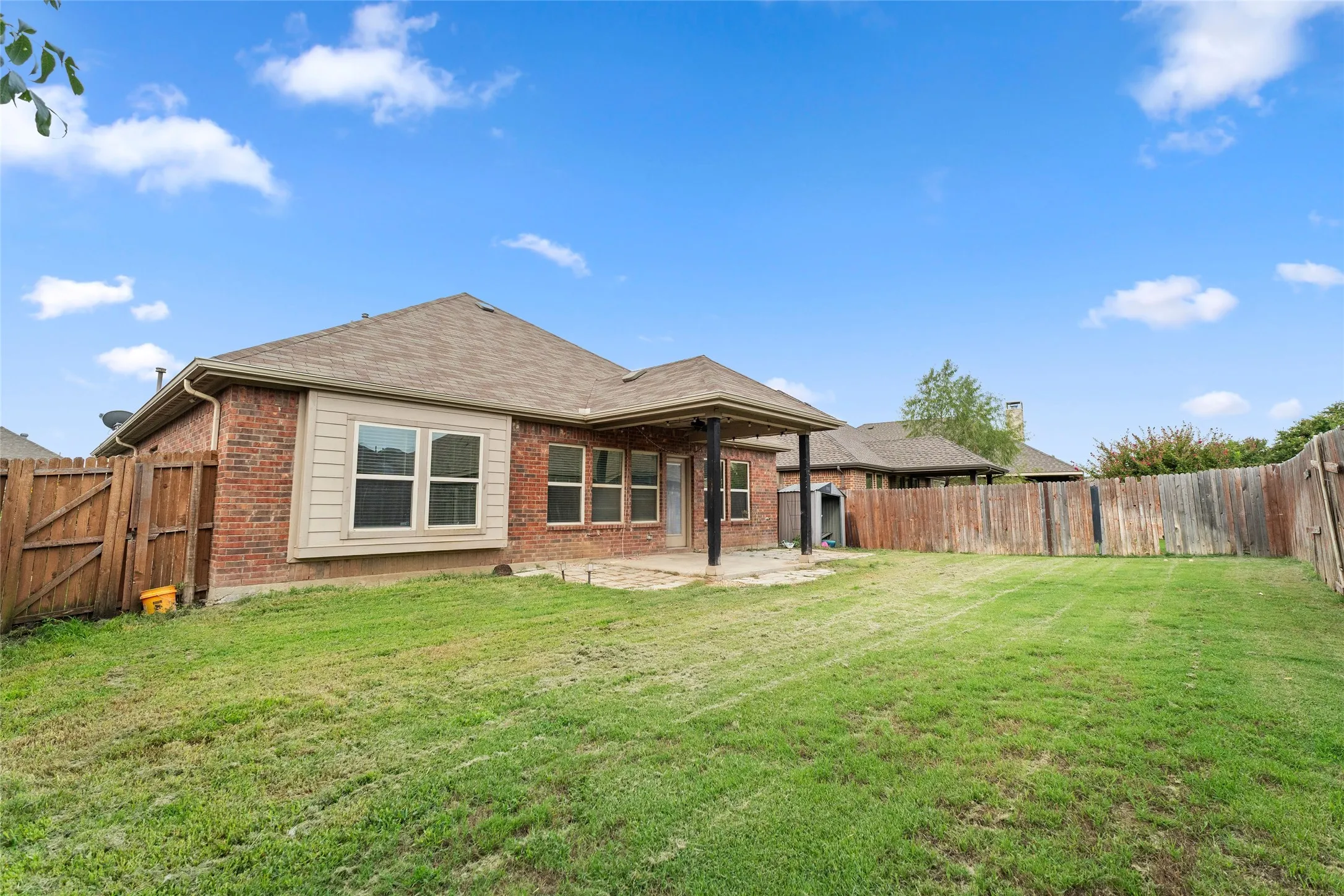 Rear view of house with a fenced backyard, a patio area, a gate, and brick siding