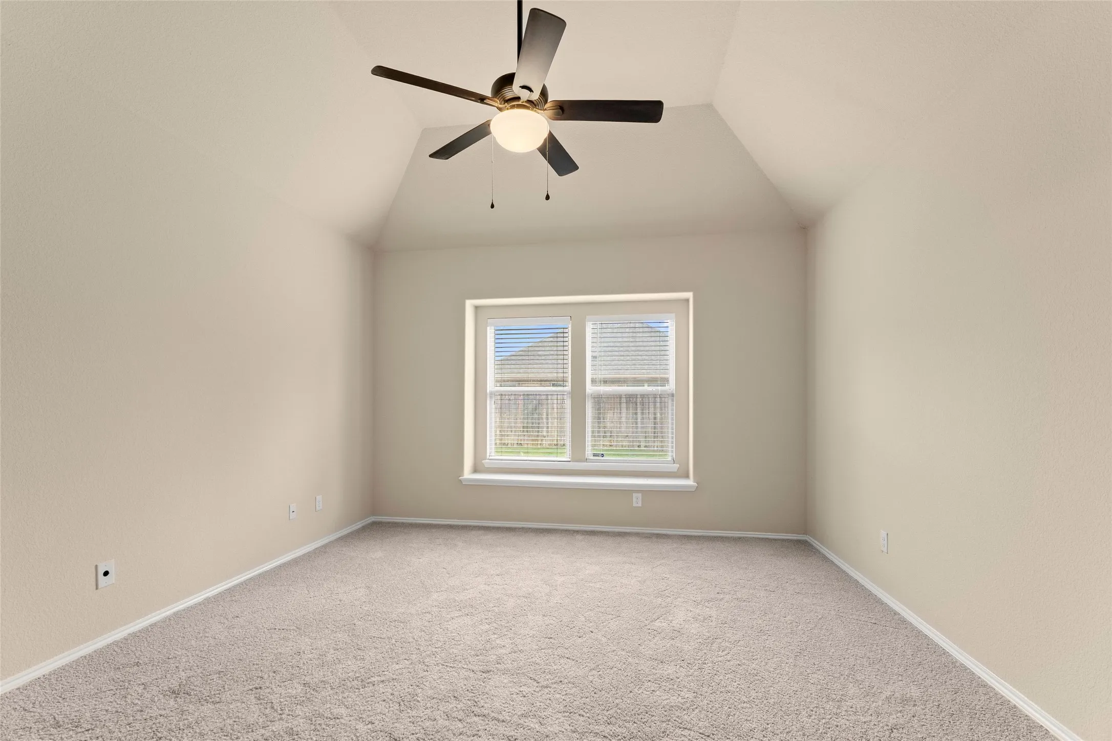Empty room with carpet floors, vaulted ceiling, and a ceiling fan