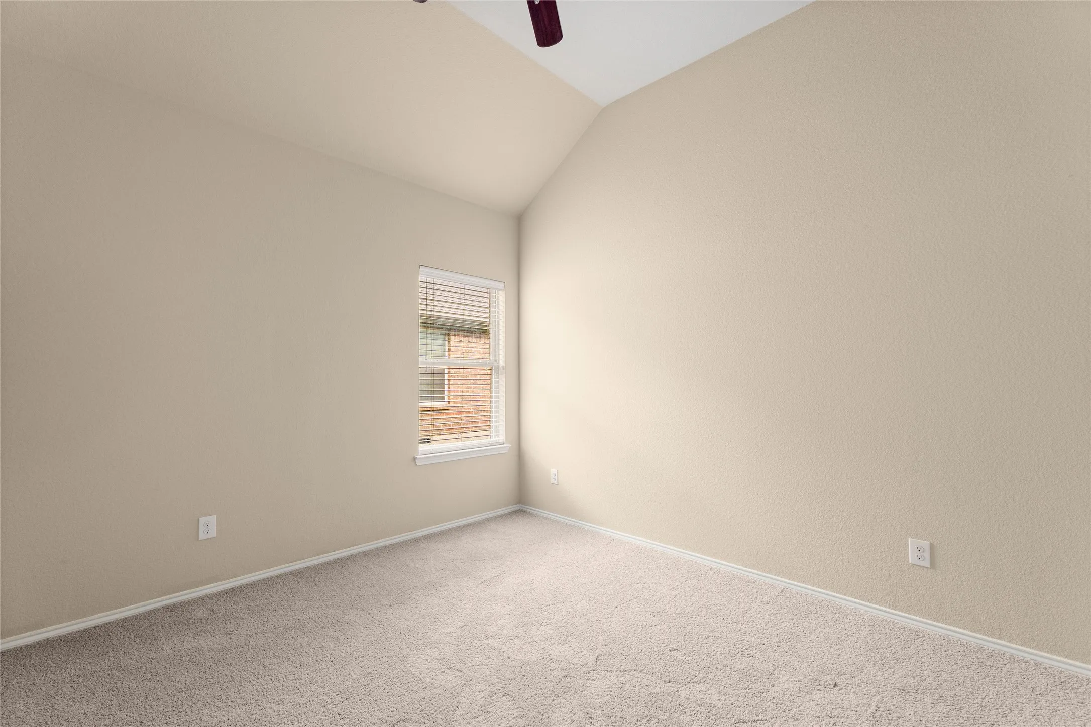 Carpeted empty room with vaulted ceiling and ceiling fan
