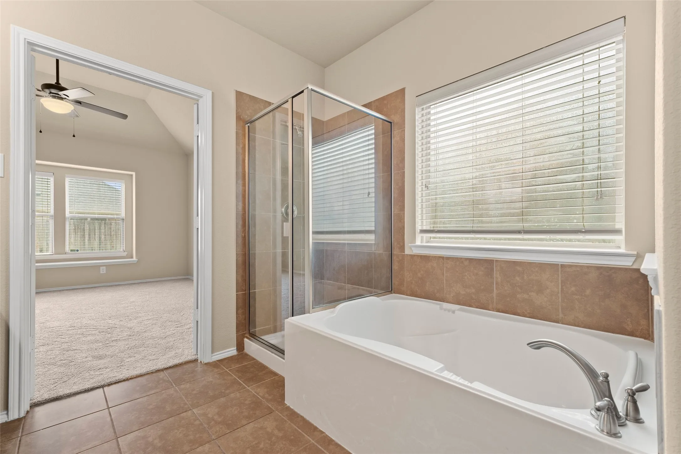 Full bath featuring light tile patterned floors, healthy amount of natural light, a bath, a shower stall, and lofted ceiling