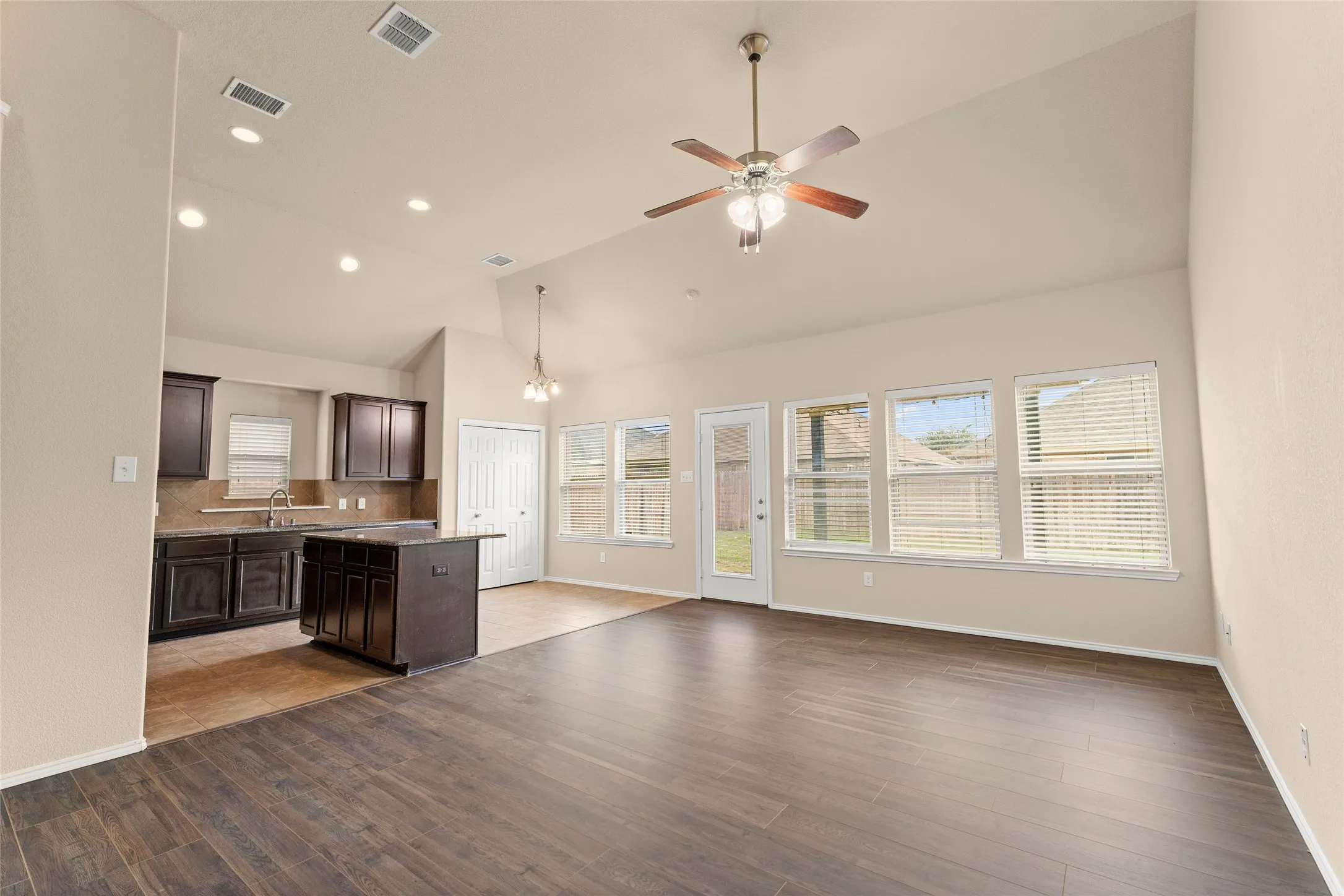 Kitchen featuring dark brown cabinetry, a chandelier, open floor plan, dark wood-type flooring, and recessed lighting
