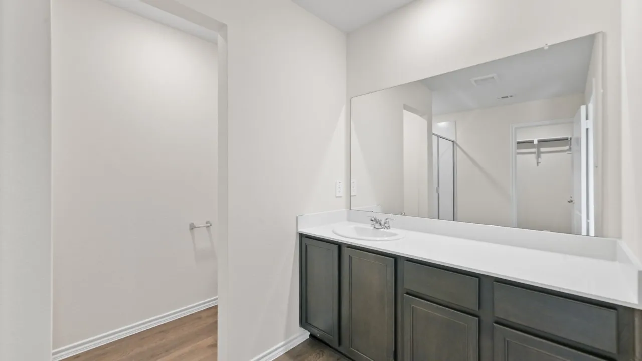 Bathroom vanity featuring a single basin, a white countertop, and dark wood-finish cabinetry
