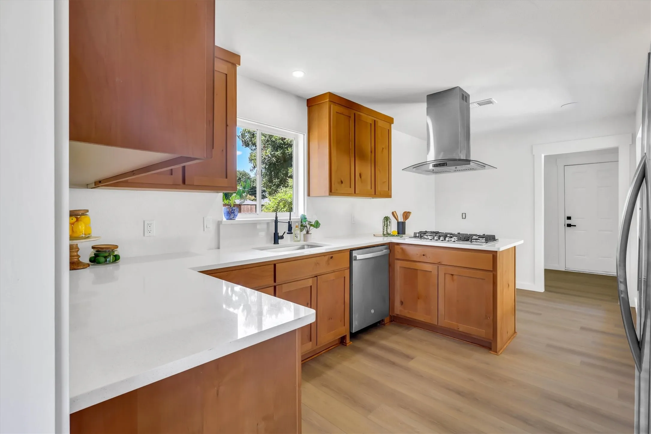 Kitchen featuring wood-finish cabinetry, white countertops, stainless steel appliances, and wood-look flooring